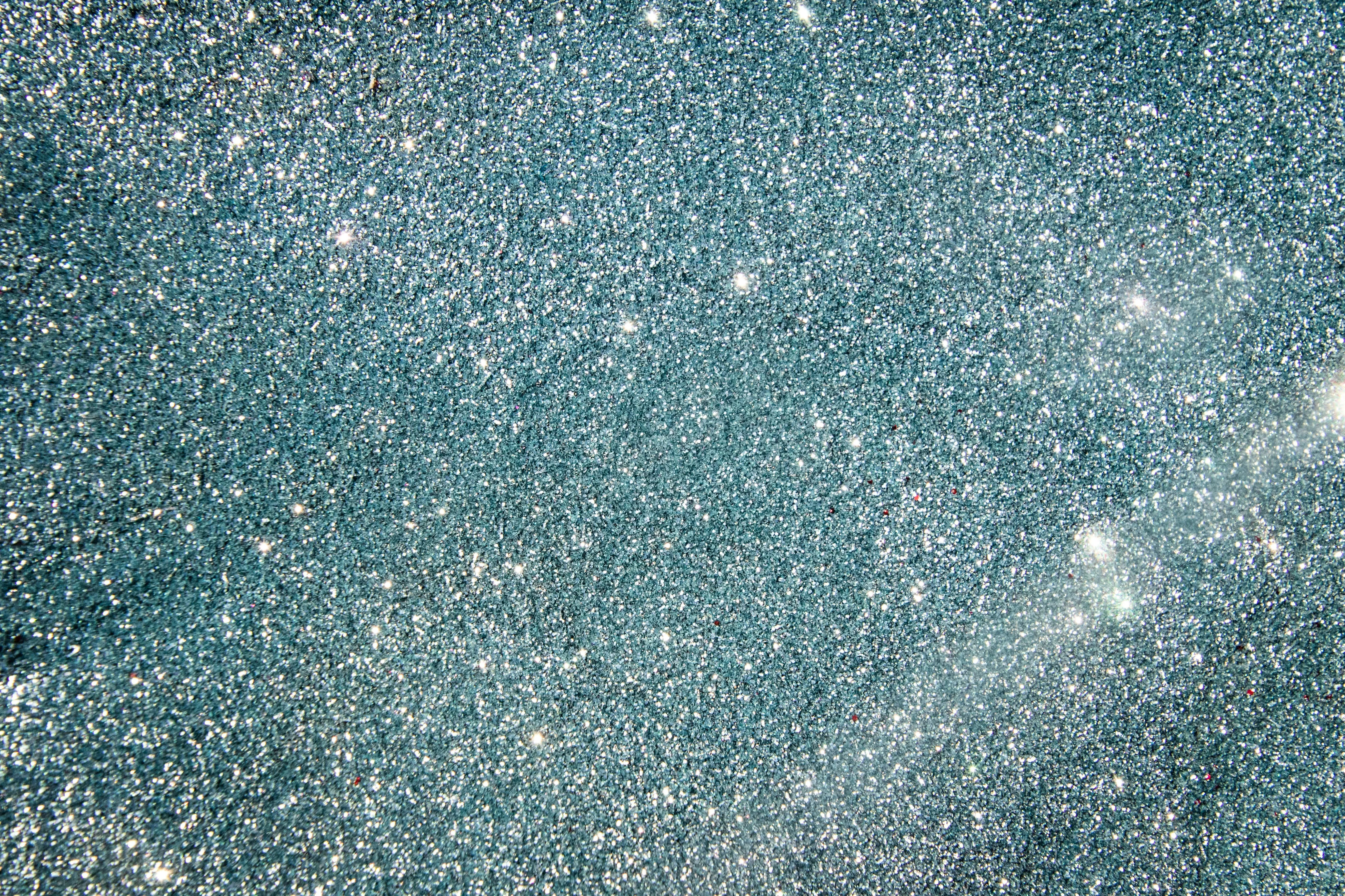 Sparkling glitter texture in soft teal and silver tones