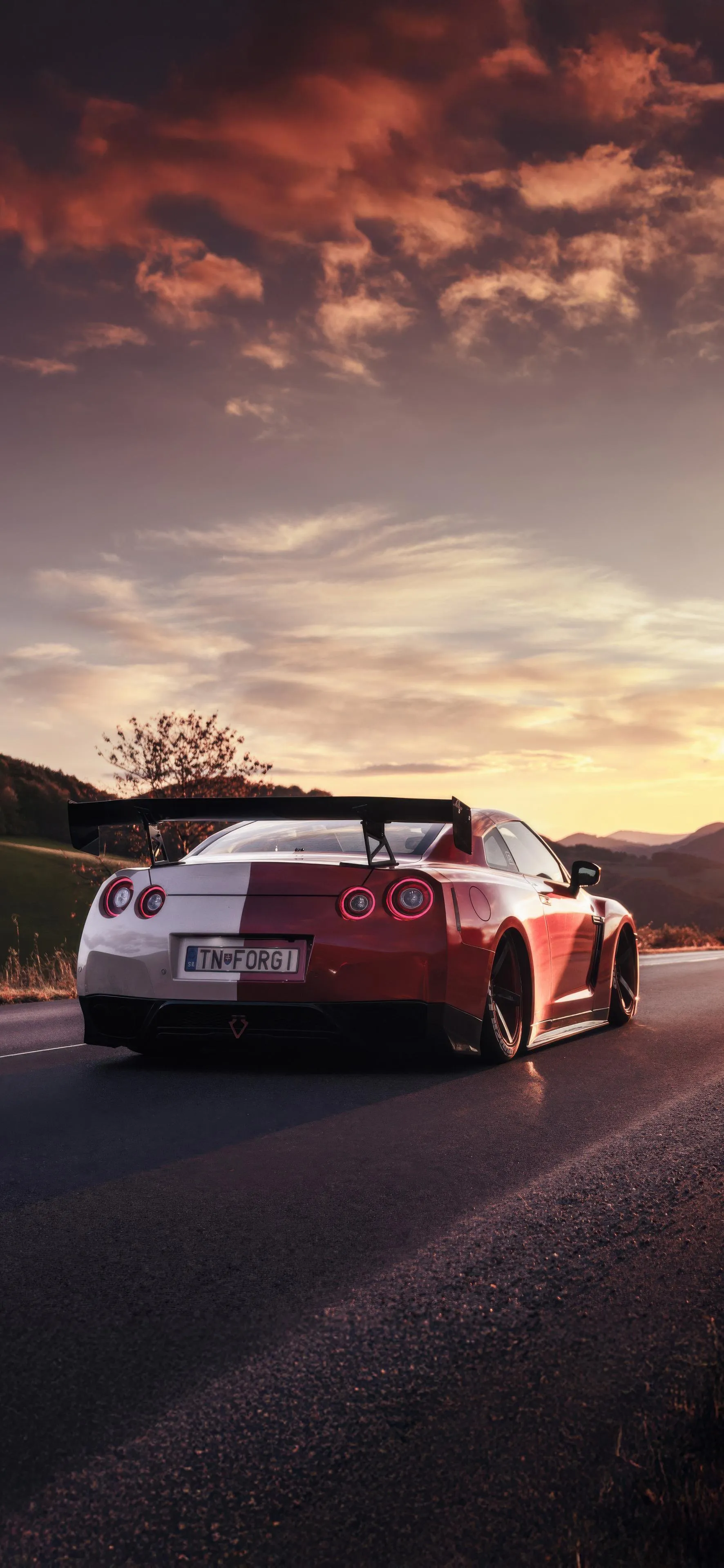 Sports Car Driving into Sunset with Dramatic Sky