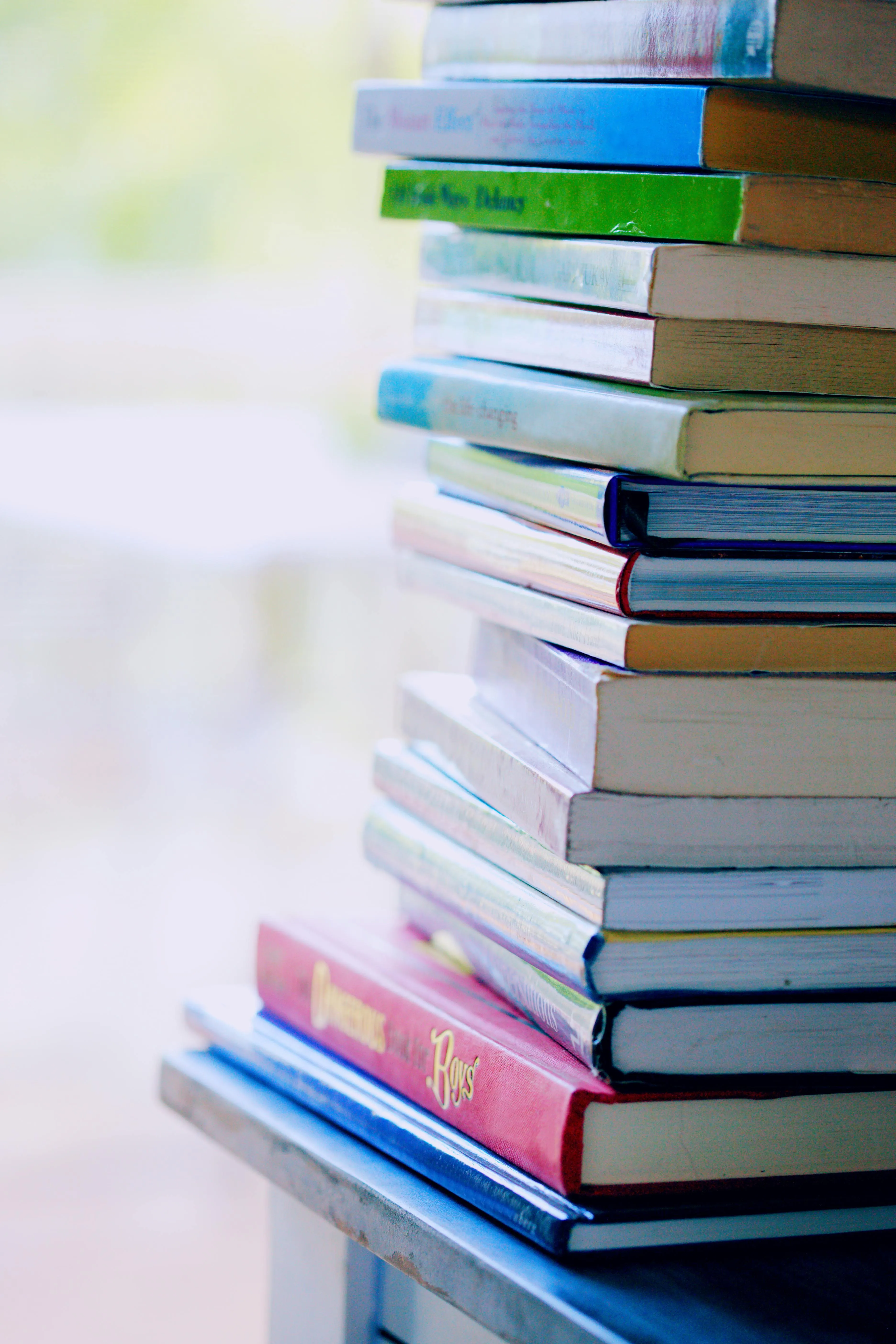 Stack of colourful books on a table with blurred background