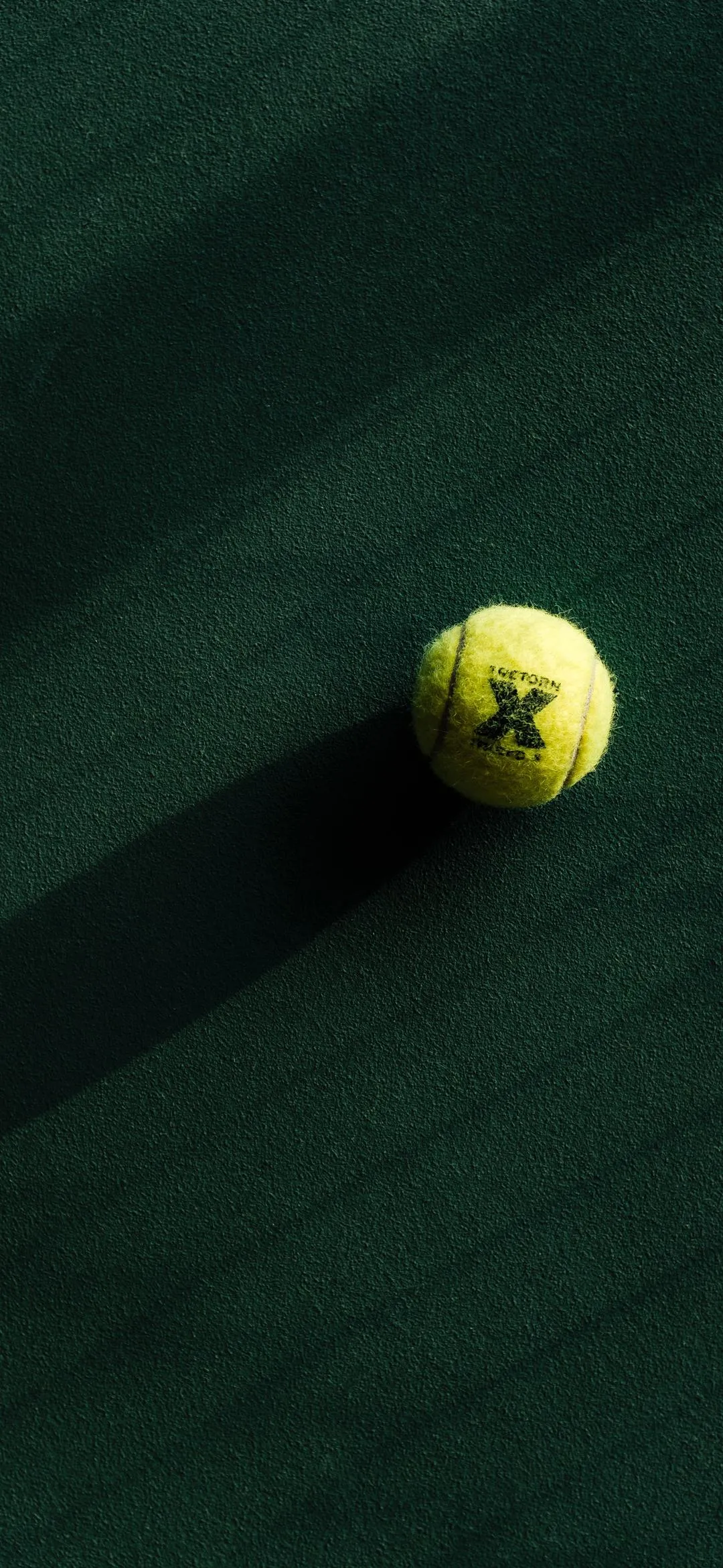 Tennis Ball on Green Court in Sharp Sunlight and Shadows