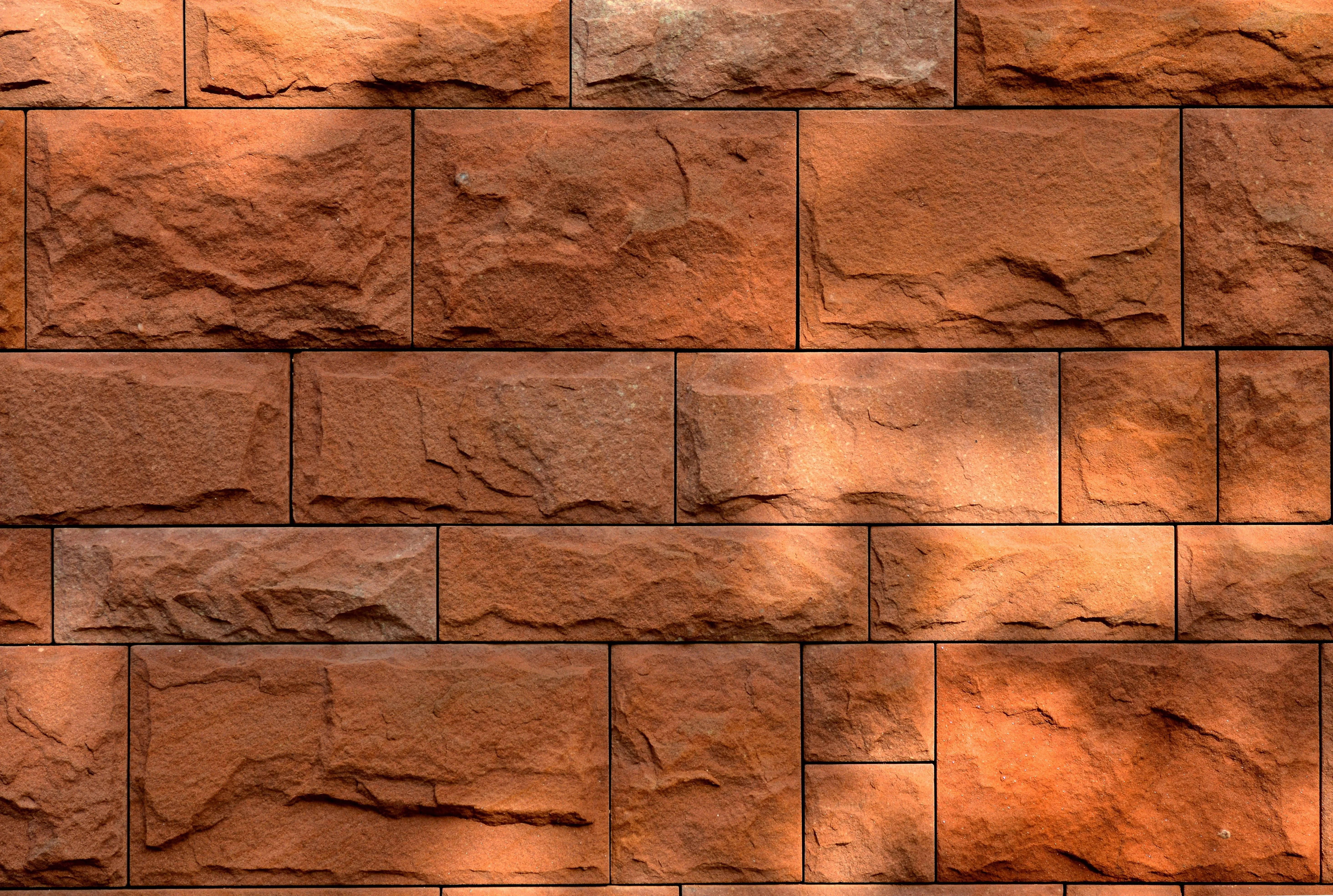 Textured red brick wall with sunlight casting soft shadows