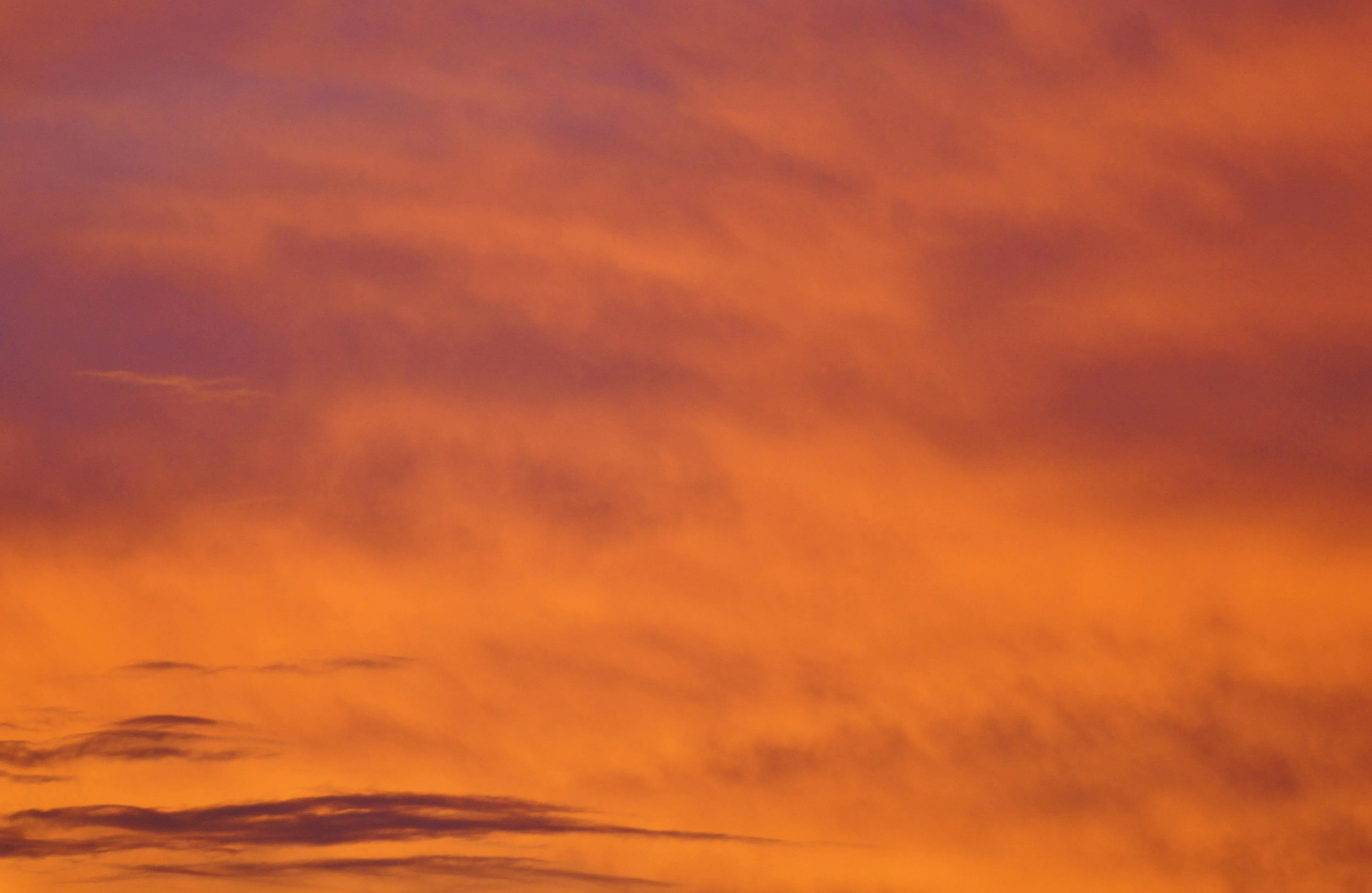 Vibrant orange sunset sky with soft cloud formations image