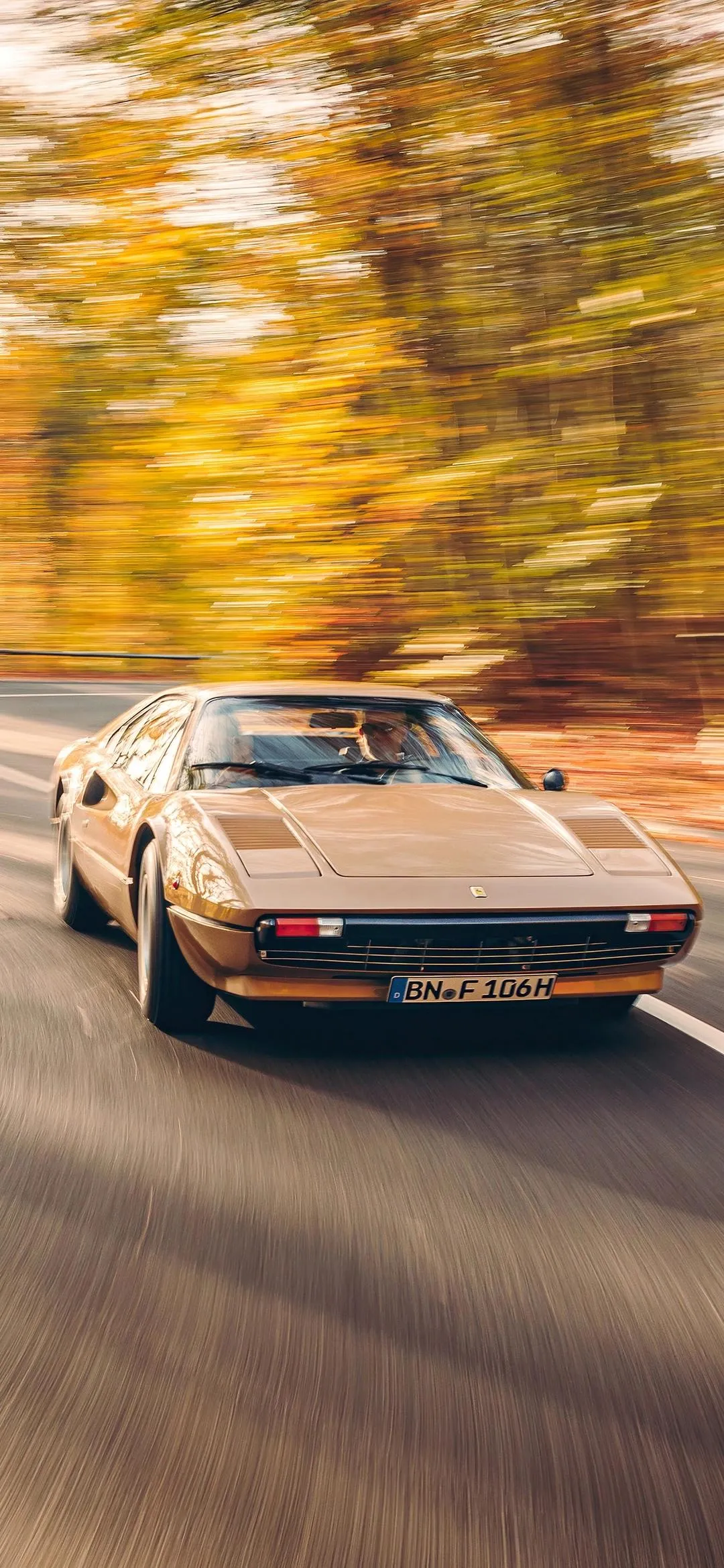 Vintage Car Driving Fast on a Tree Lined Road in Fall