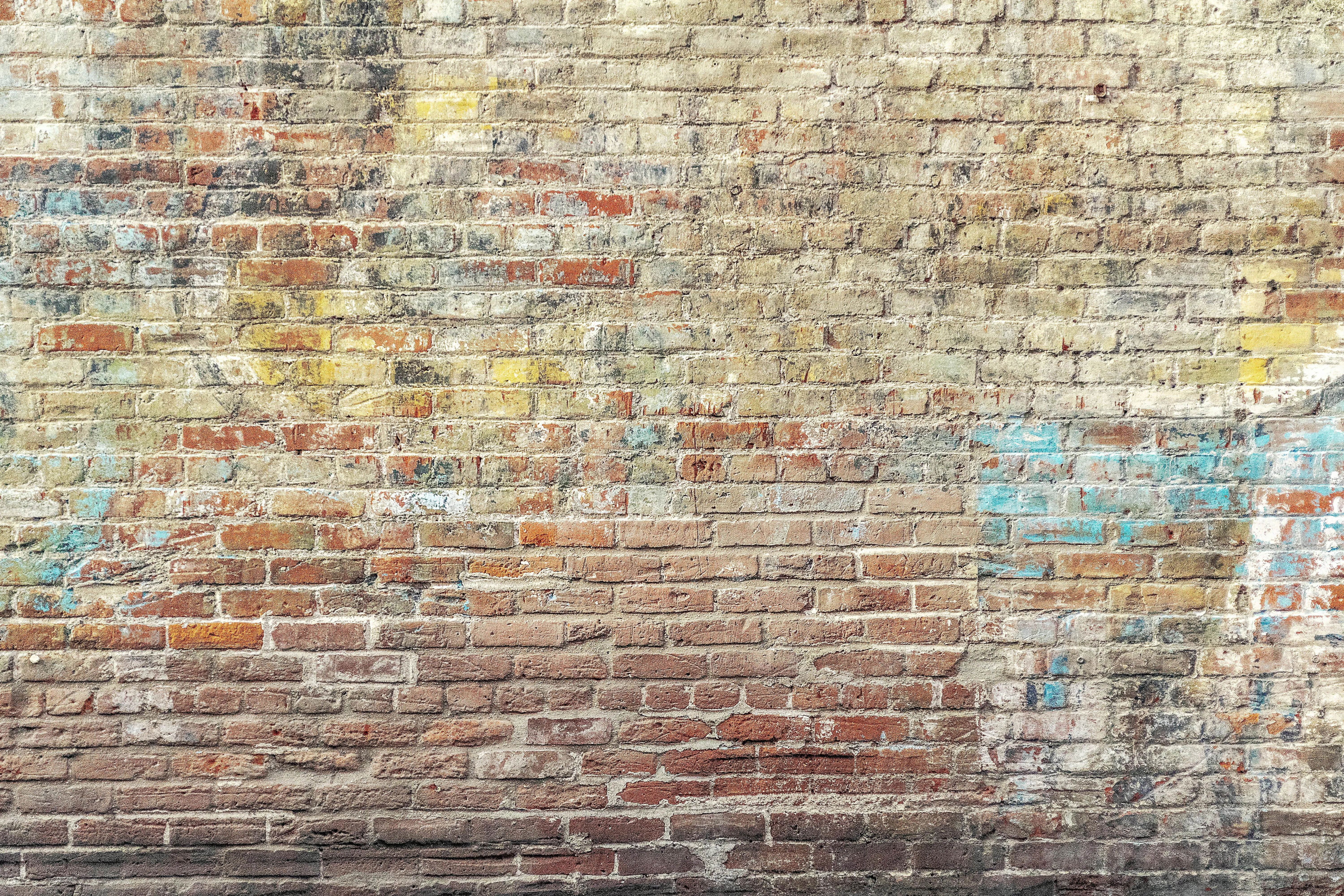 Weathered brick wall with faded paint and graffiti Wallpaper