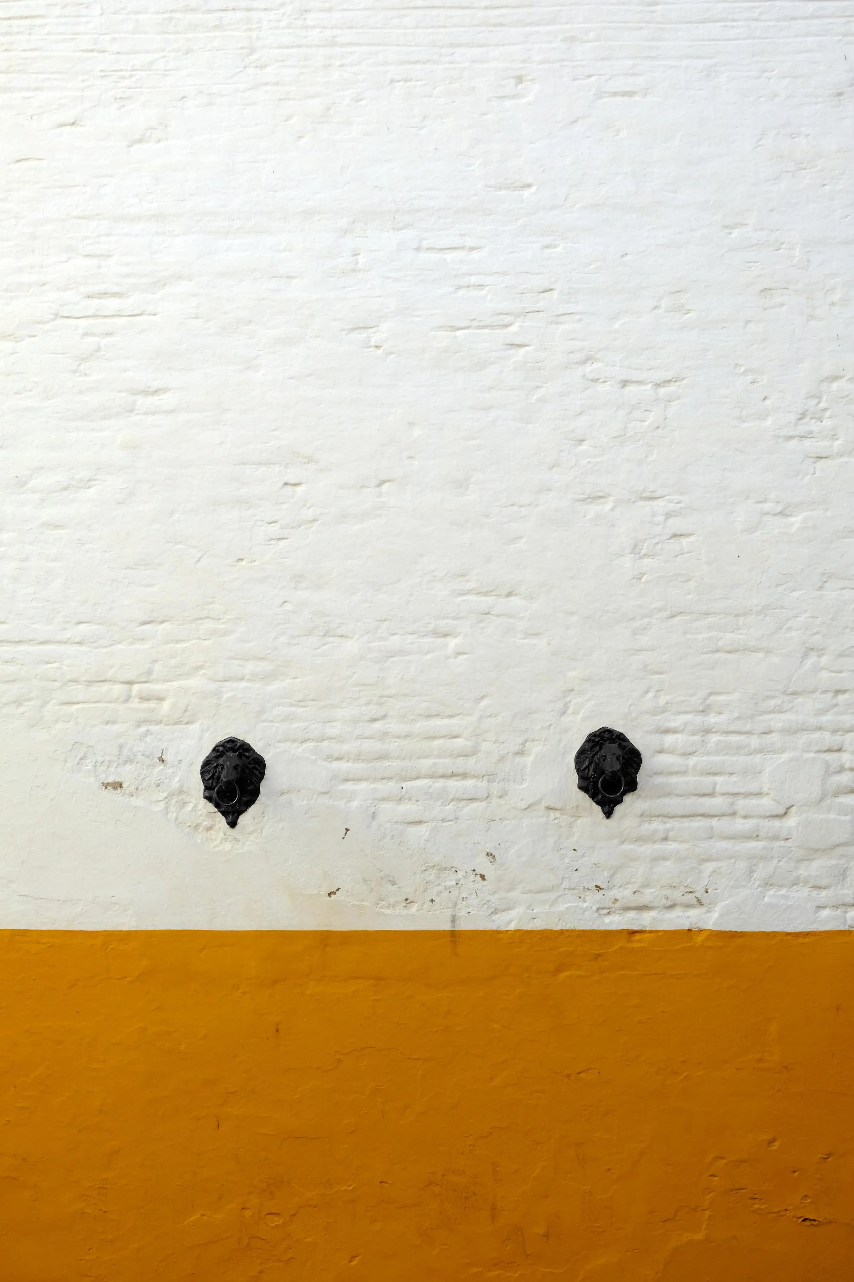 White and yellow wall with two small black water tap image