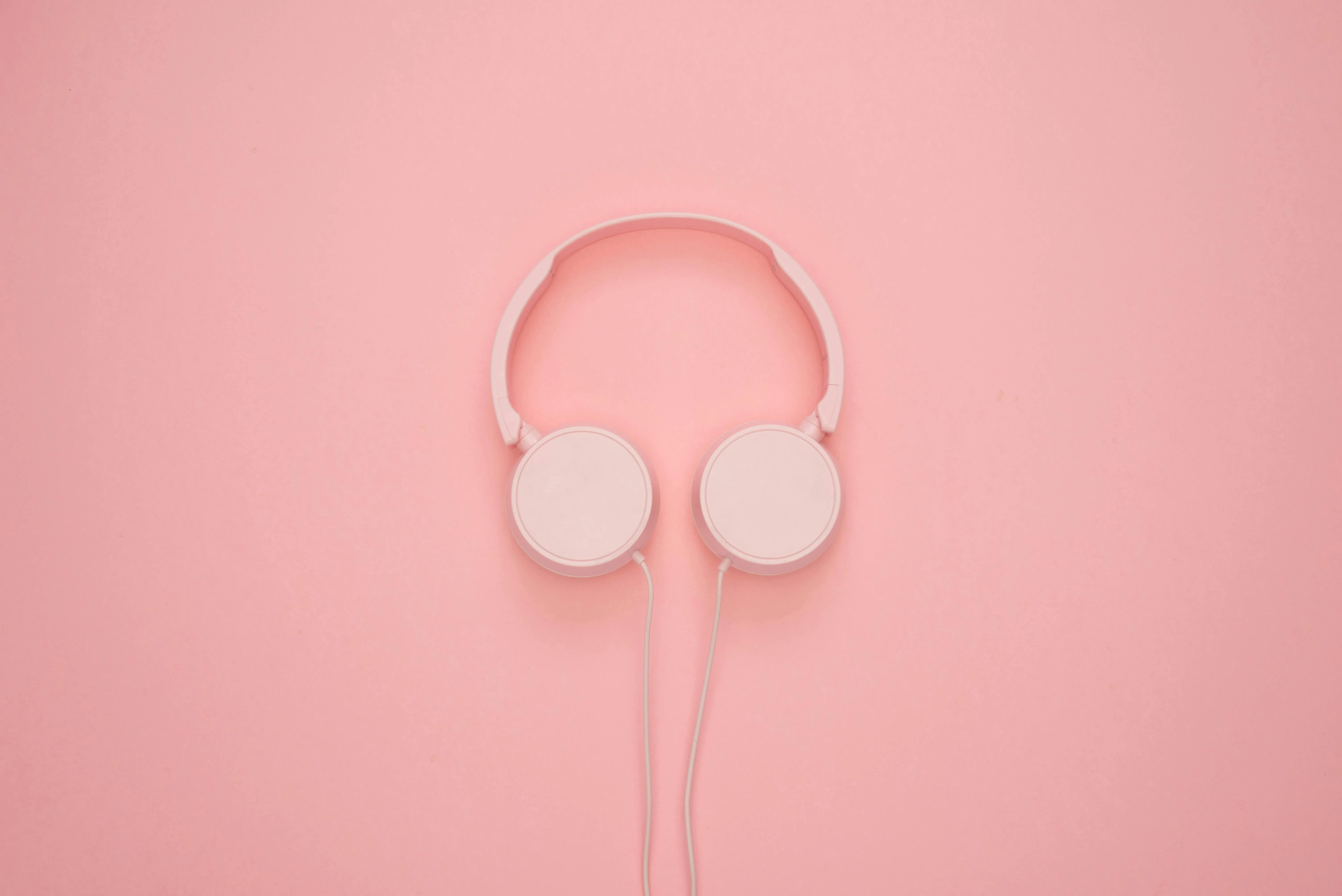 White headphones on a soft pink background free Wallpaper