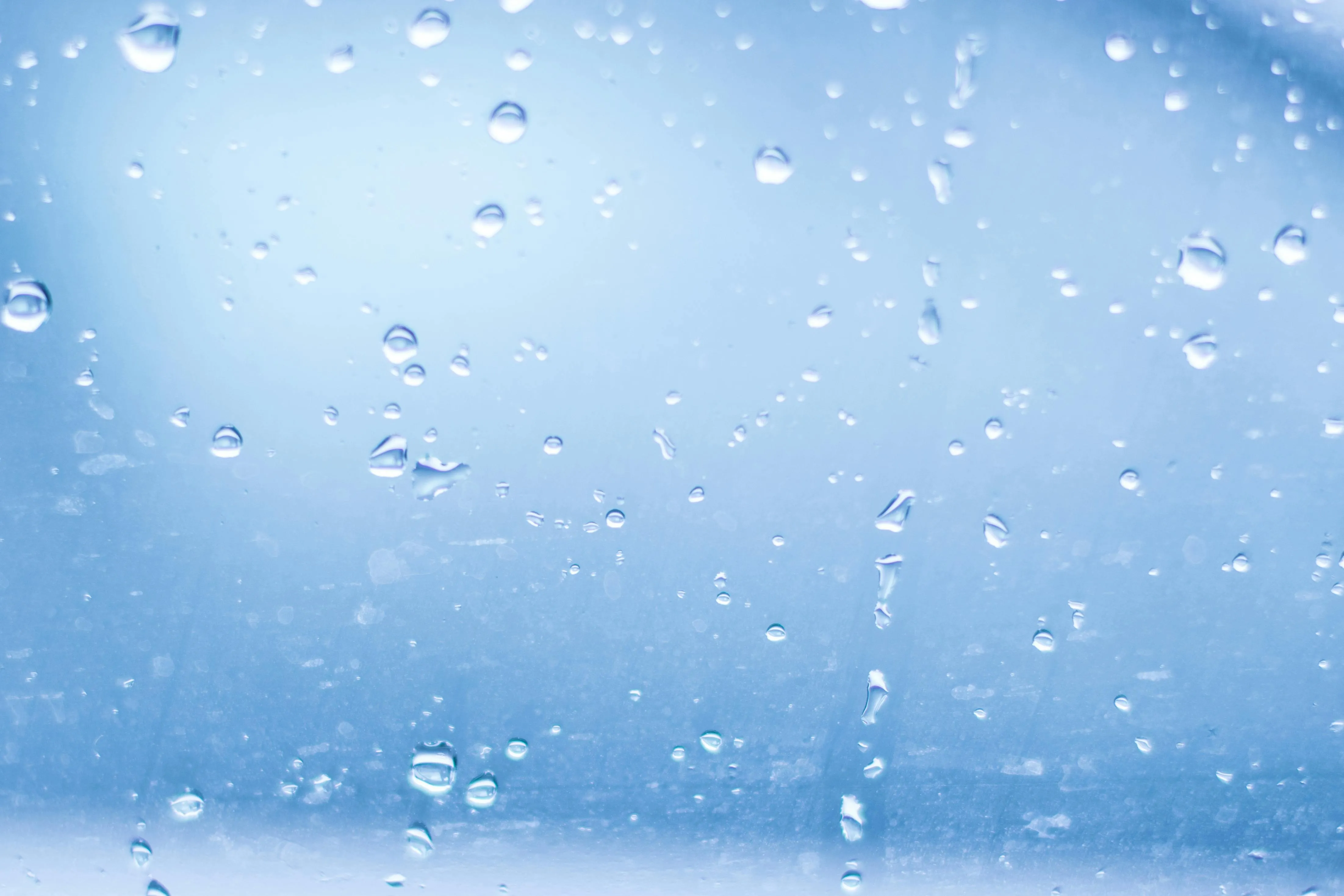 Window covered in rain droplets with blue lighting Wallpaper