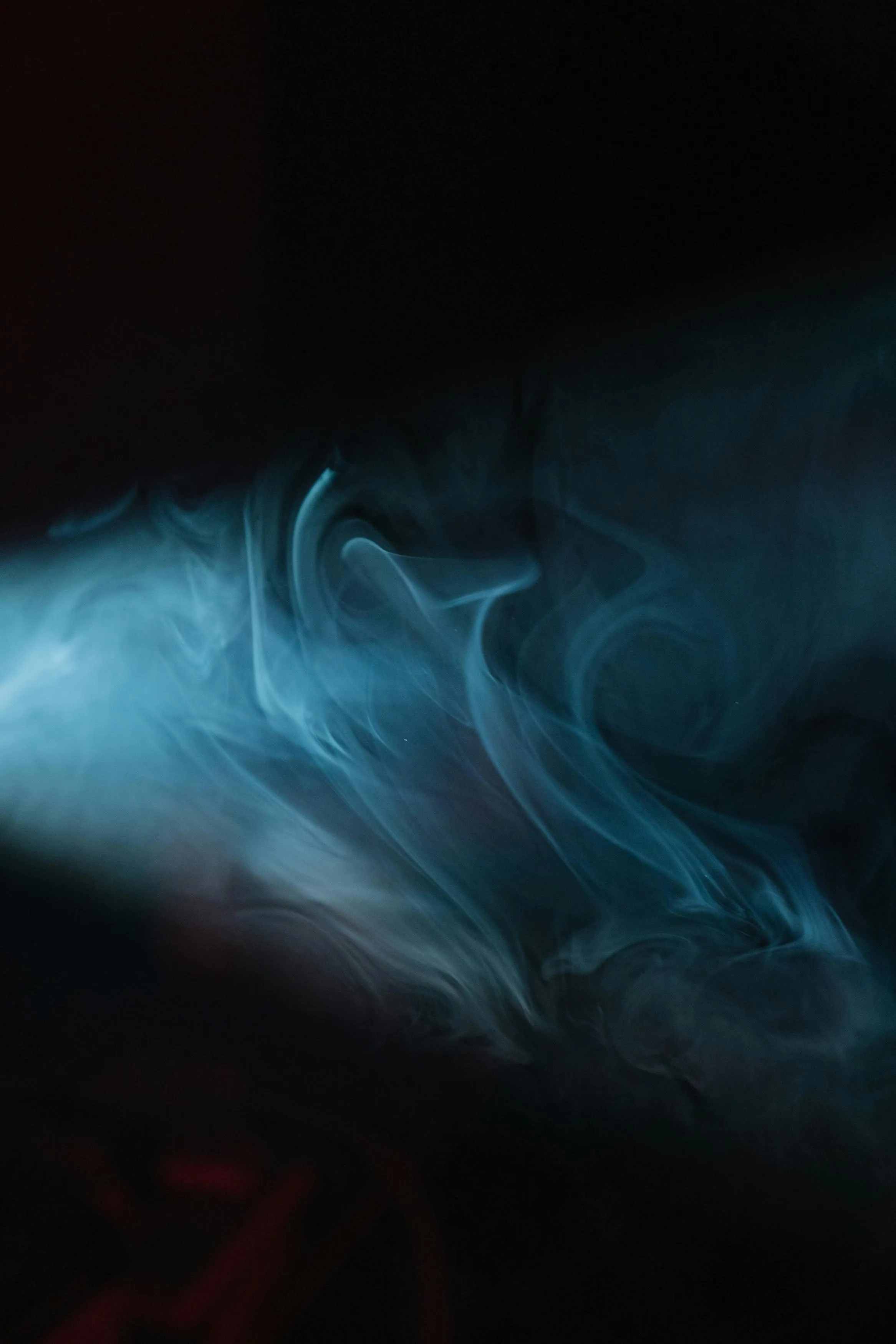Wisps of blue smoke swirling on a black background Wallpaper
