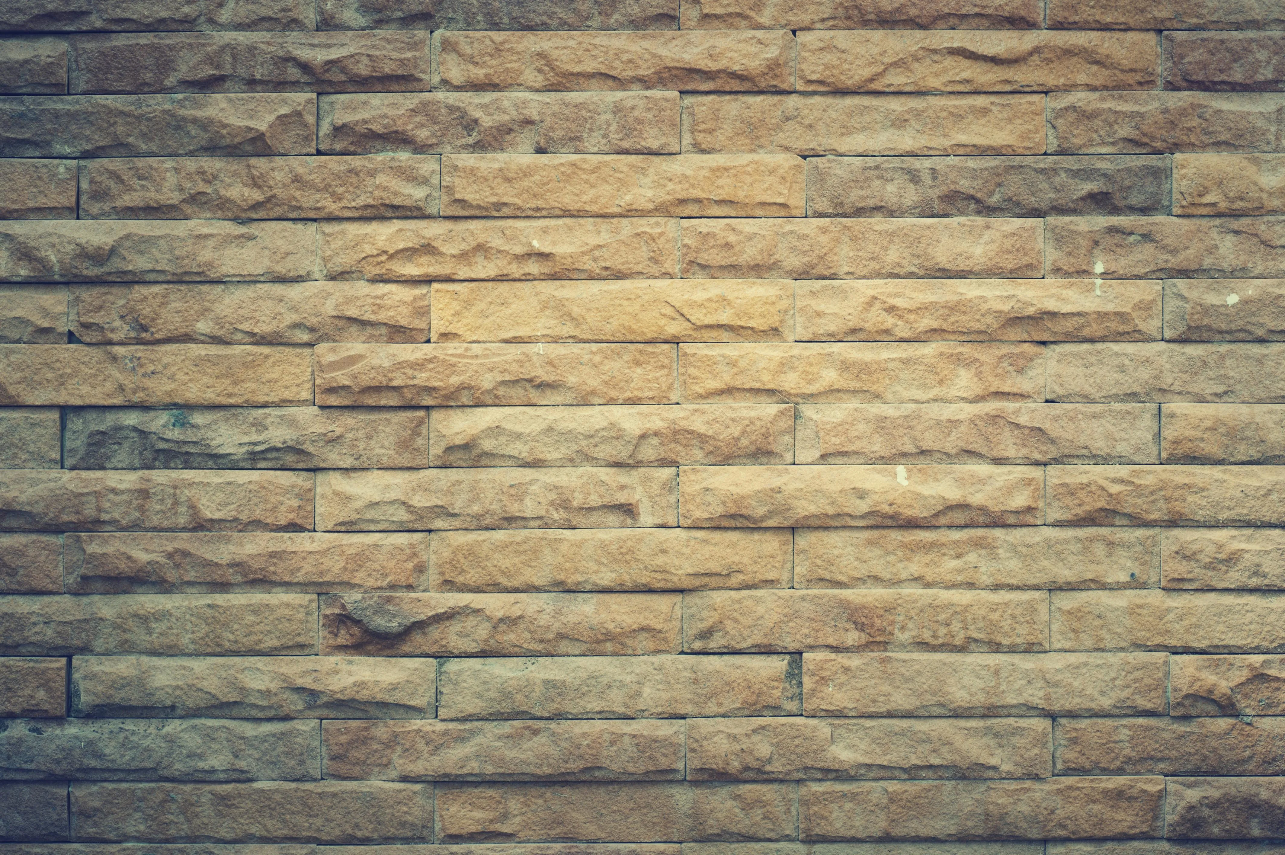 Yellowish stone brick wall with an aged appearance Wallpaper