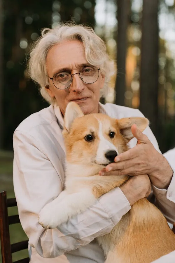 Elderly Man Lovingly Holding a Corgi Dog in His Arms Image