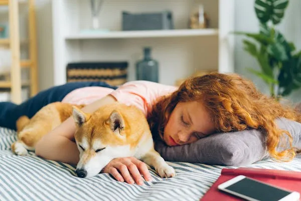 Girl Sleeping Peacefully with Her Dog on a Cozy Bed Image