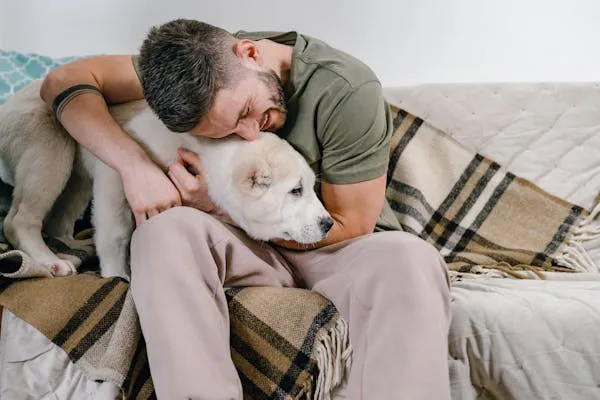 Man Cuddling His White Puppy on Sofa in a Cozy Moment