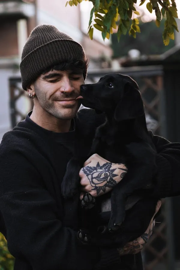 Man in Cap Holding a Black Puppy Smiling Together Image