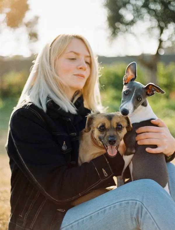 White Hair Woman Holding Two Happy Dogs Outside Wallpaper