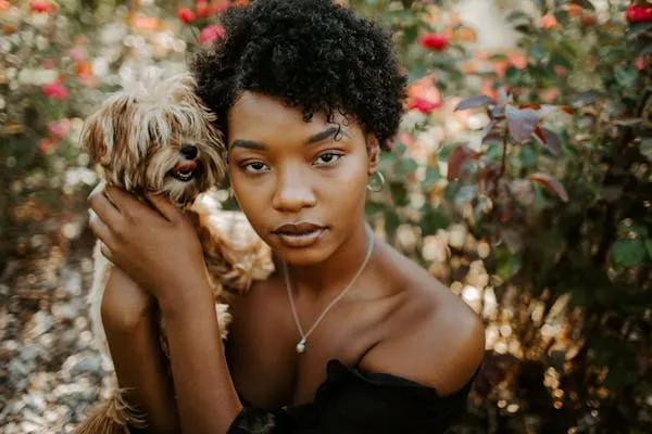 Woman Holding a Dog in a Garden Full Of Blooming Roses