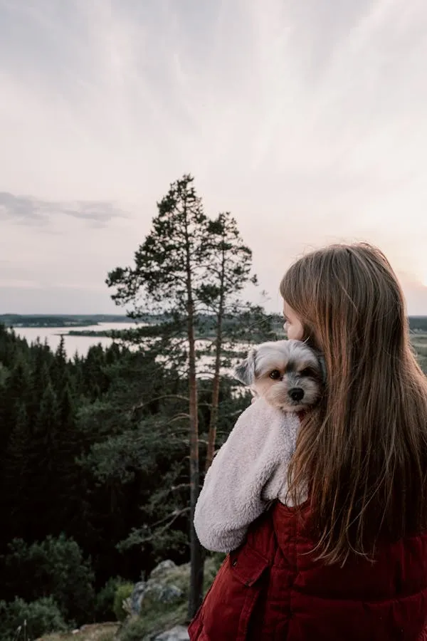 Woman Holding Small Dog with Scenic Forest and Lake View