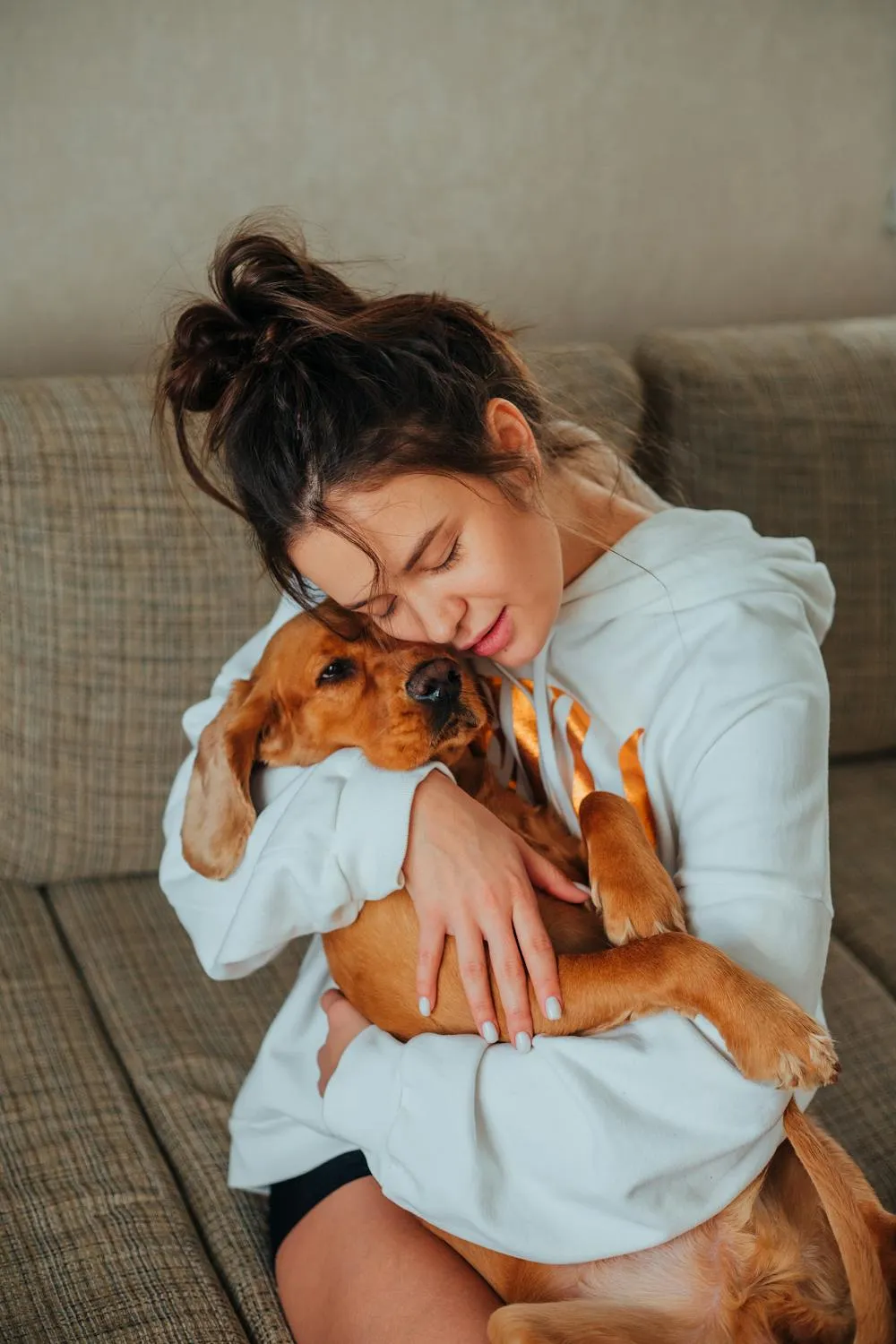 Woman Hugging Her Brown Dog Lovingly on Sofa Wallpaper