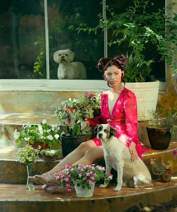 Woman in Pink Sitting with Dog Surrounded By Flowers