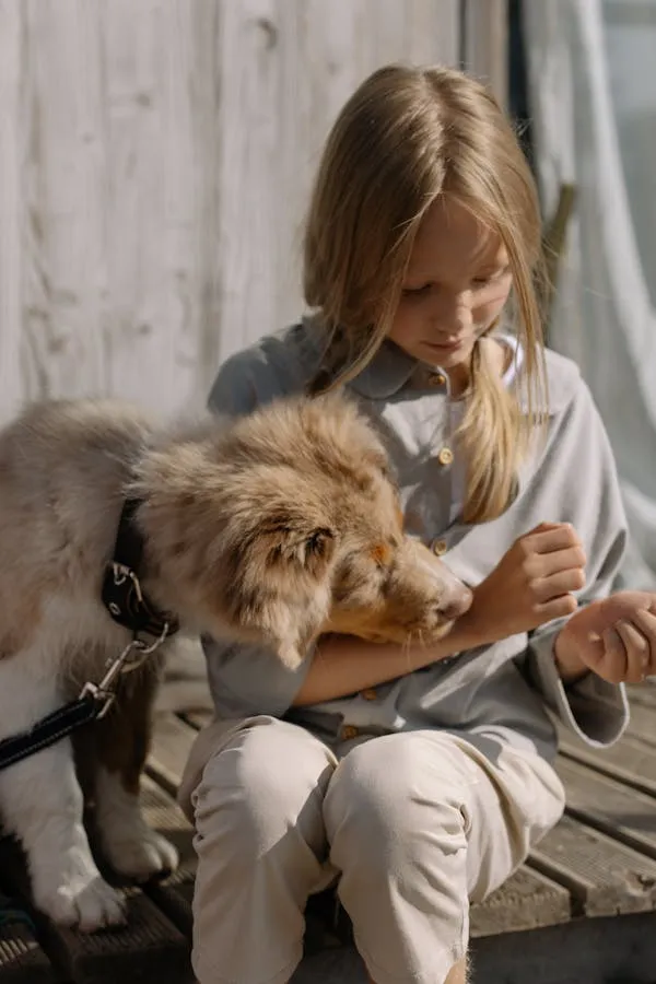 Young Girl Sitting with Dog Sniffing Her Arm Free Wallpaper