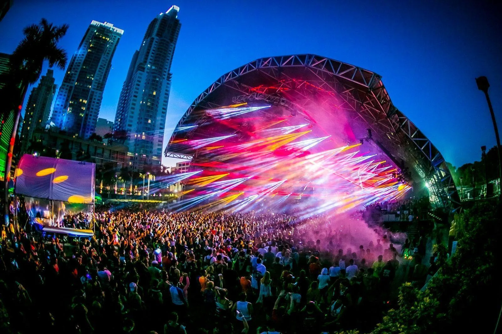 Colourful Edm Festival Crowd Under City Skyline Lights