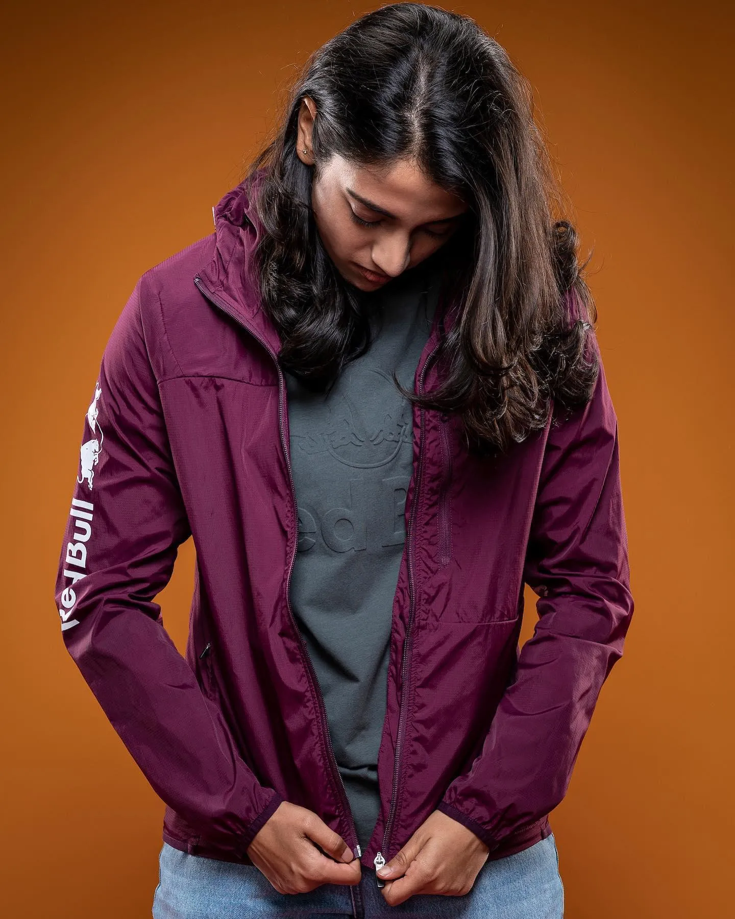 Smriti dressed in a hoodie standing against brown wall