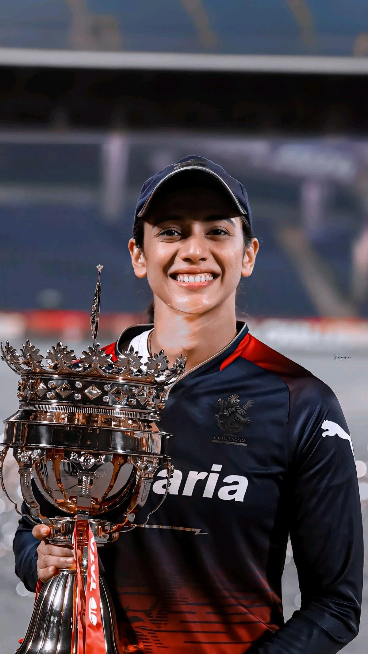 Smriti in sportswear smiling at a stadium with crowd