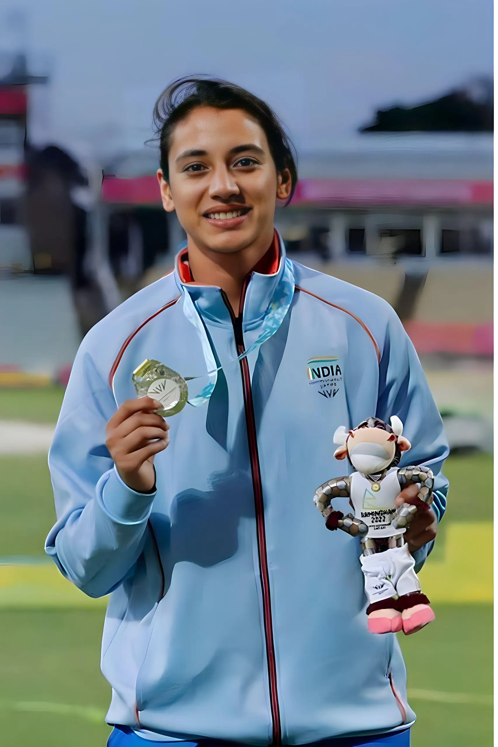 Smriti Mandhana holding a cricket bat smiling at the camera