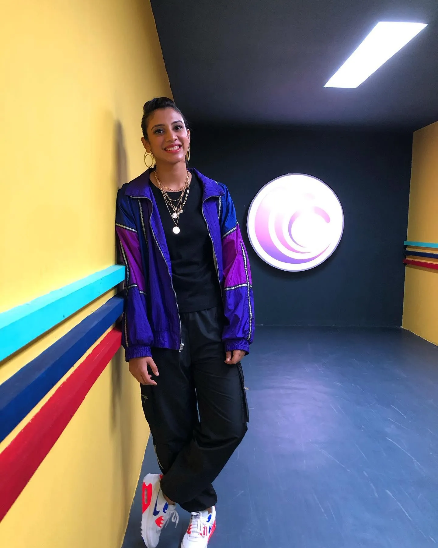 Smriti Mandhana in a colorful outfit posing confidently