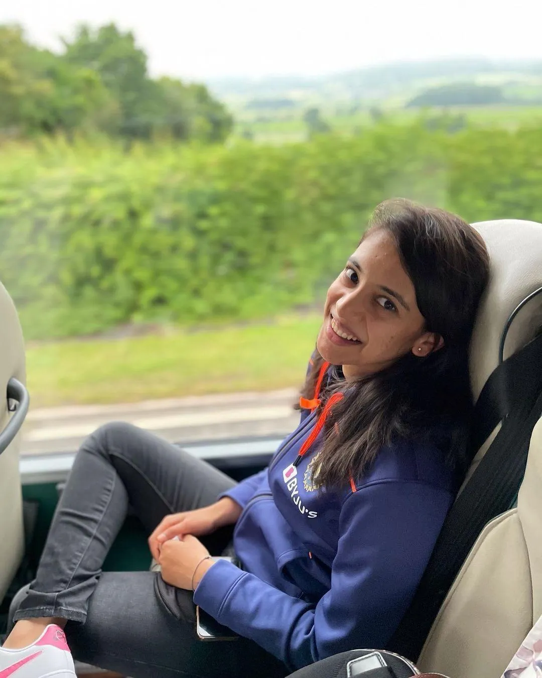 Smriti Mandhana posing casually in a car with a smile