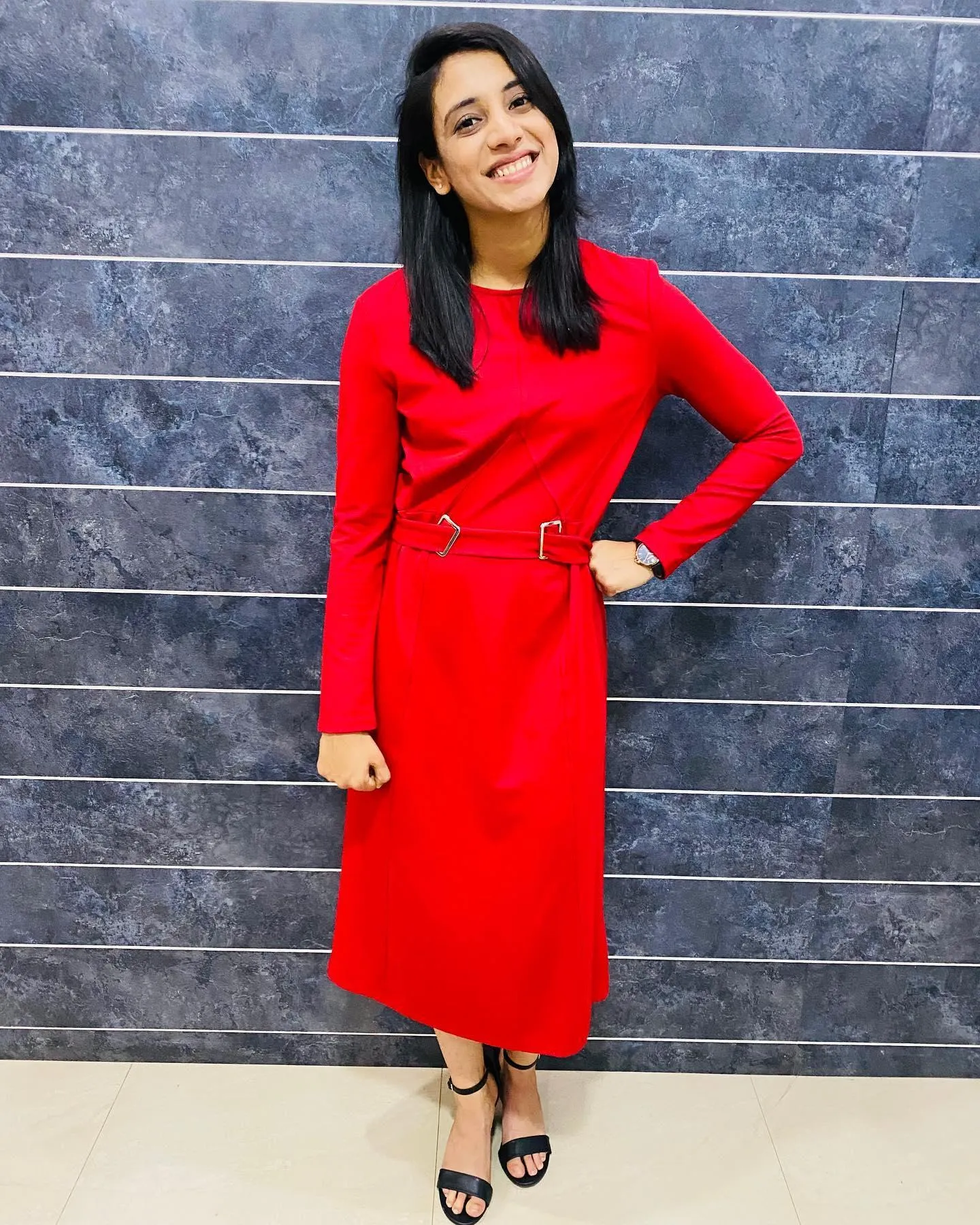 Smriti Mandhana posing confidently in bright red dress