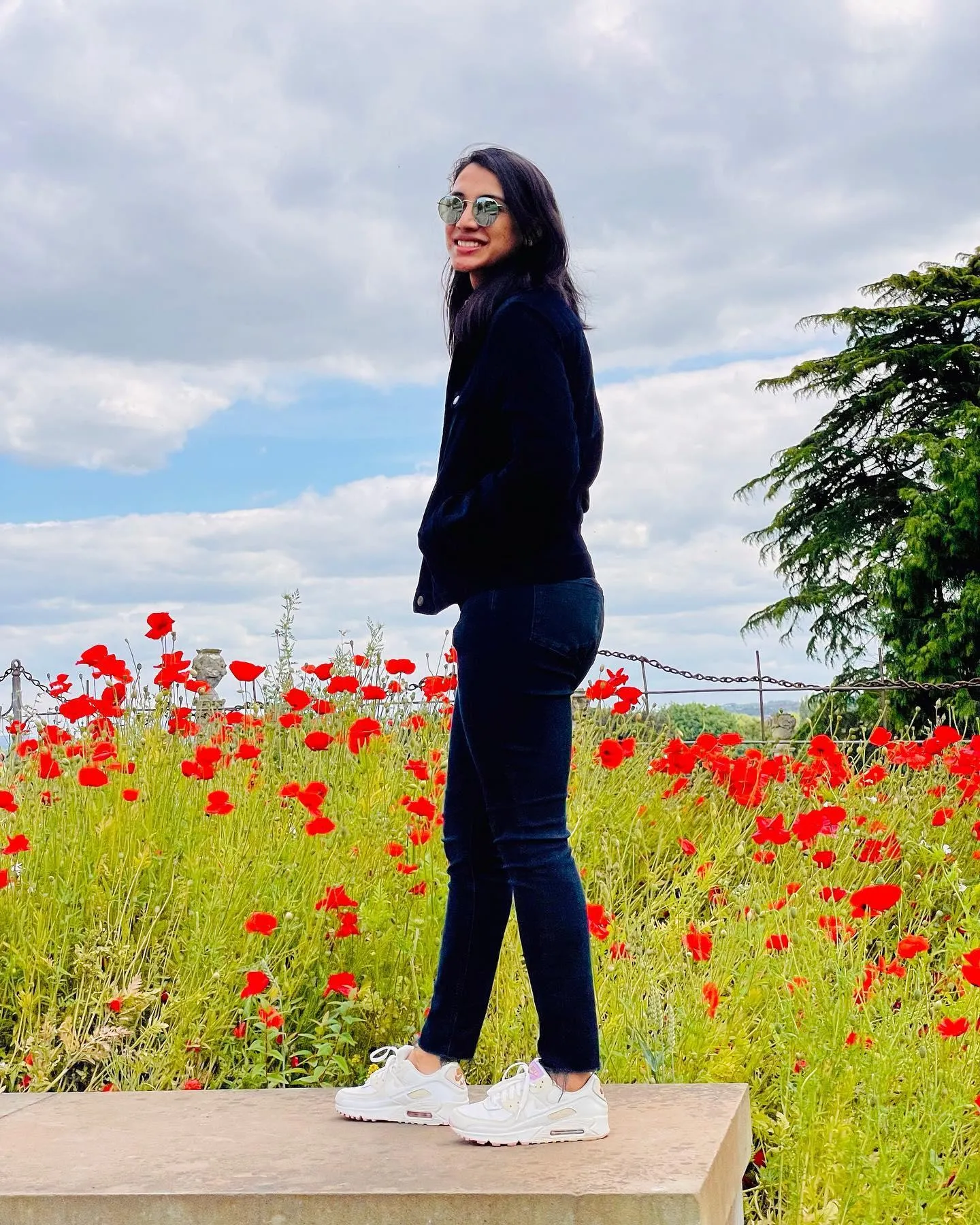 Smriti Mandhana posing in front of a colorful flower field