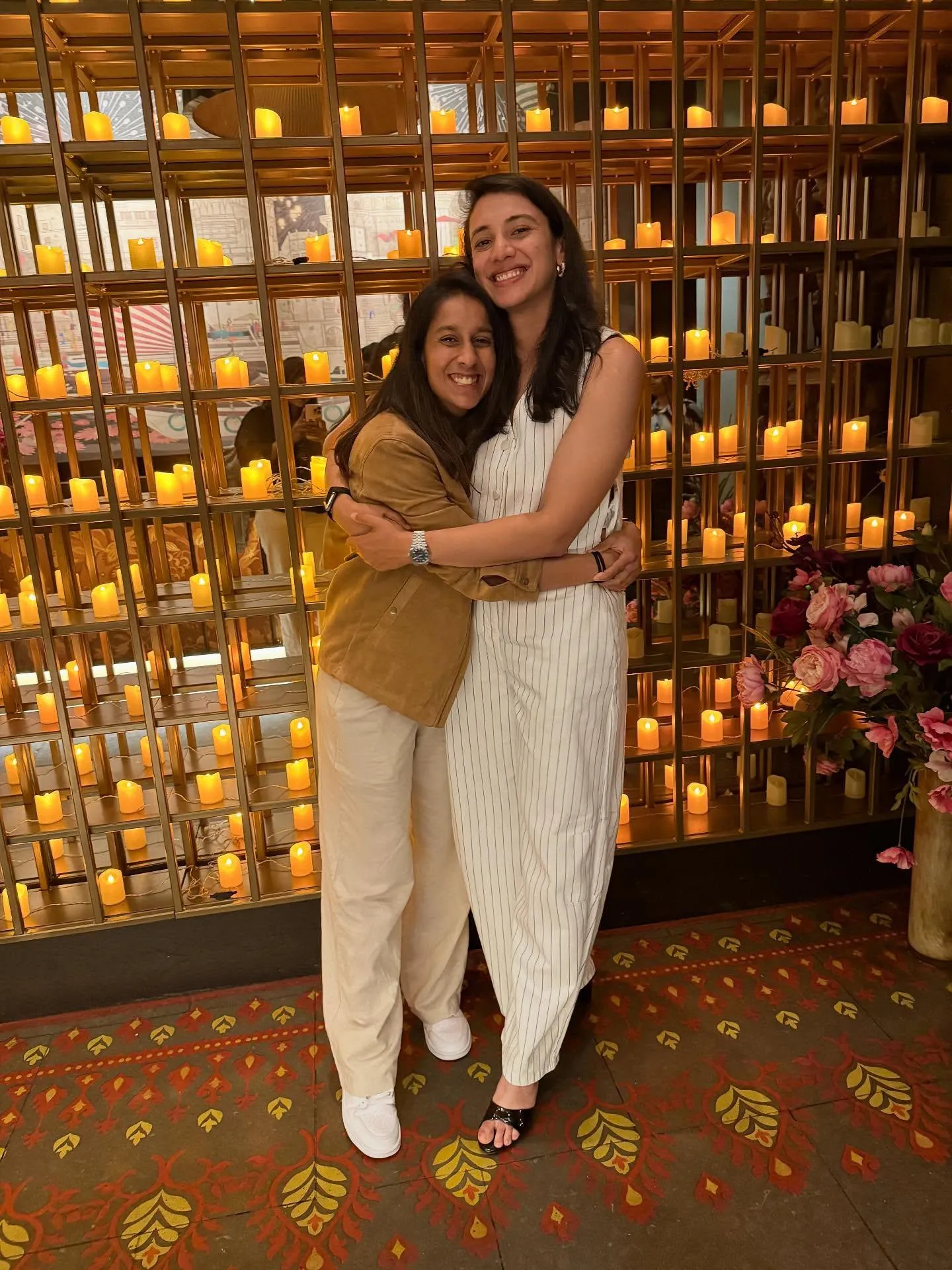 Smriti Mandhana posing in front of a shelf of trophies