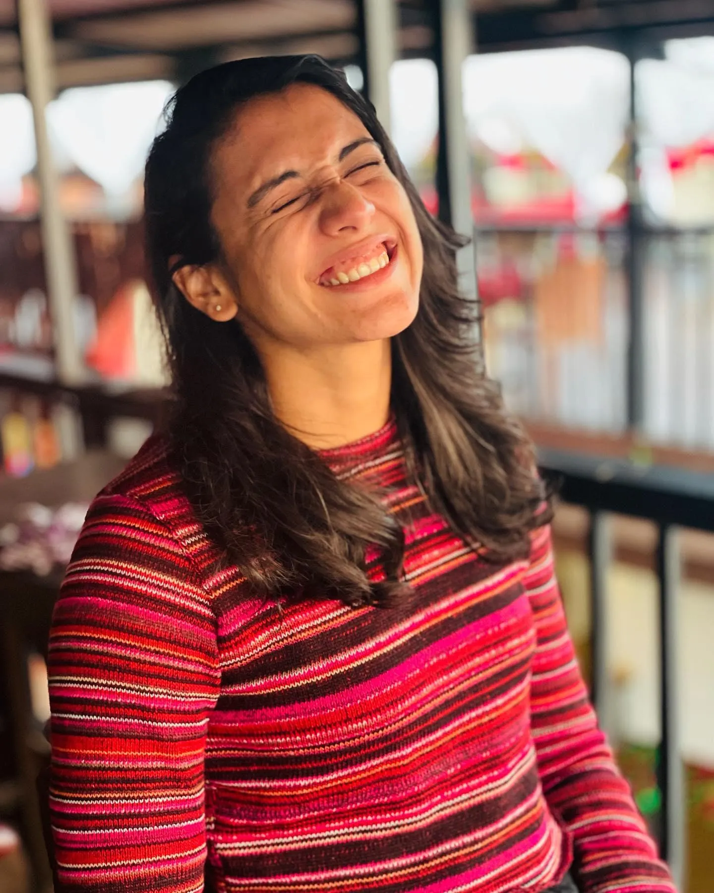 Smriti Mandhana smiling brightly wearing a red striped sweater