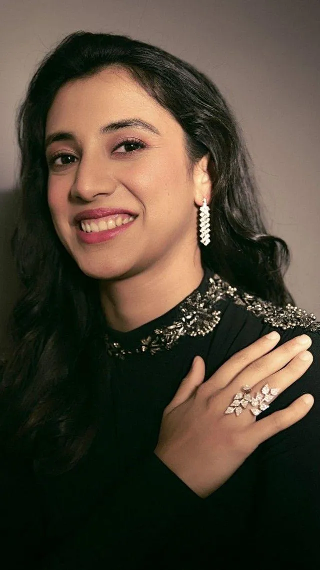 Smriti Mandhana smiling in black dress holding award