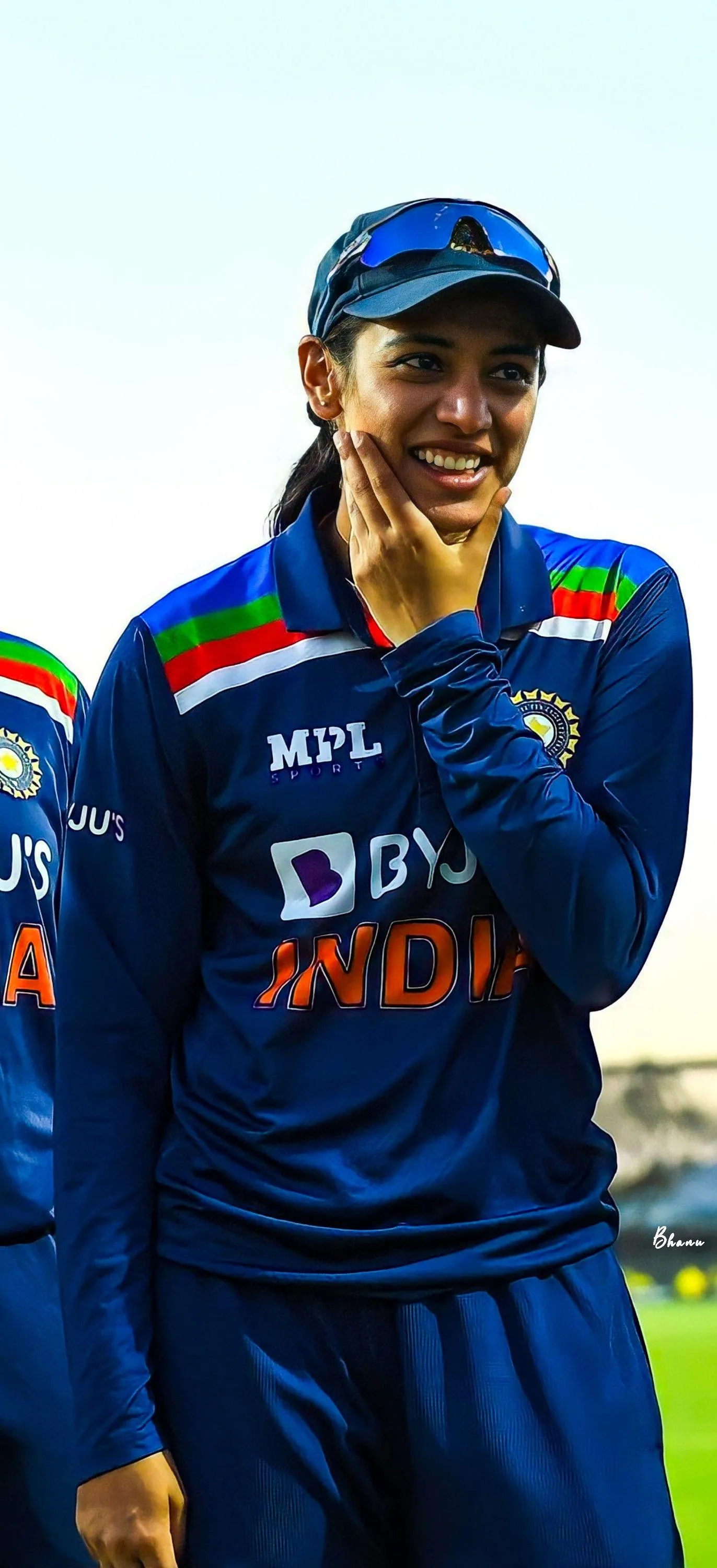 Smriti Mandhana smiling in team jersey on cricket field