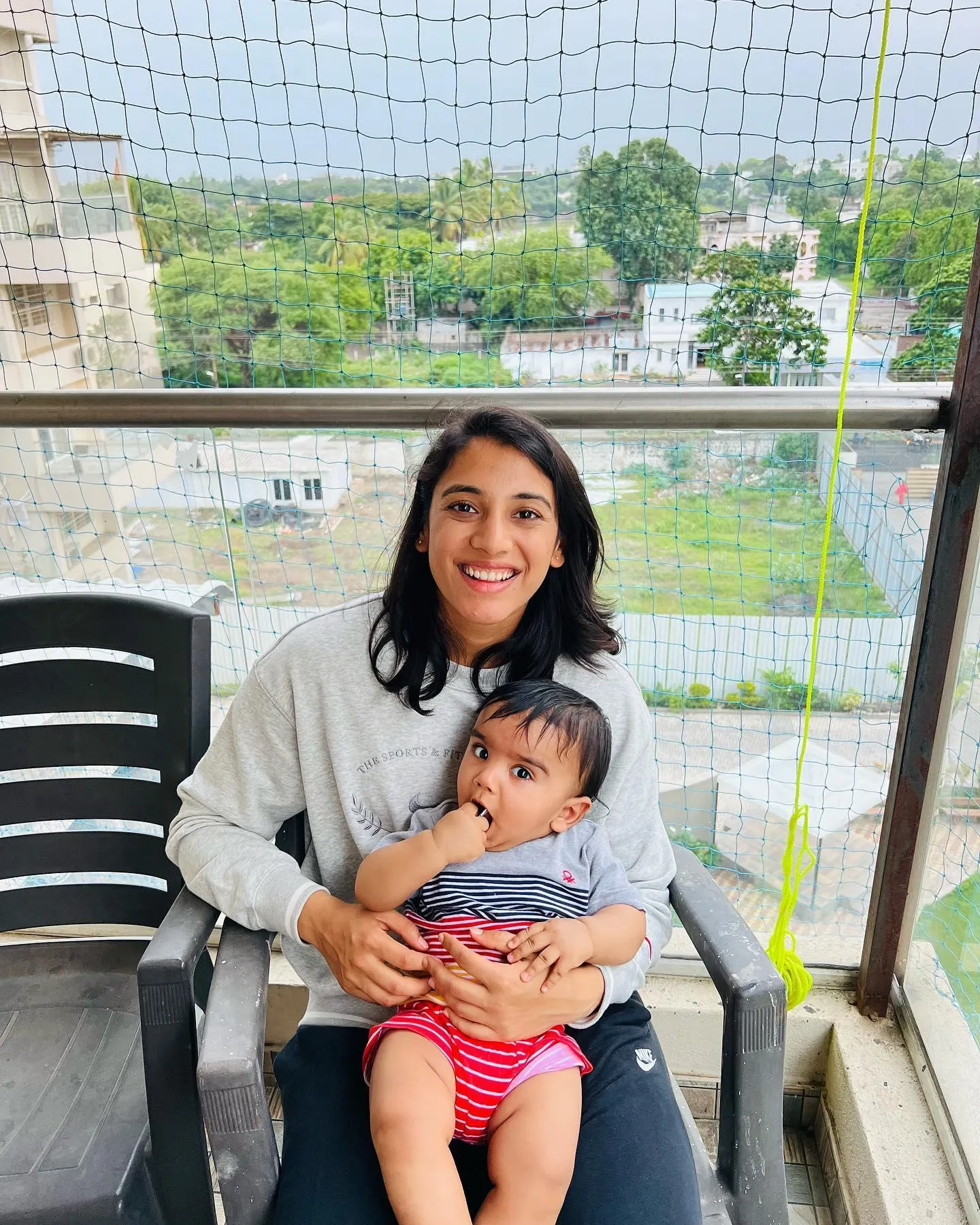 Smriti Mandhana smiling on balcony with coffee and mountain view