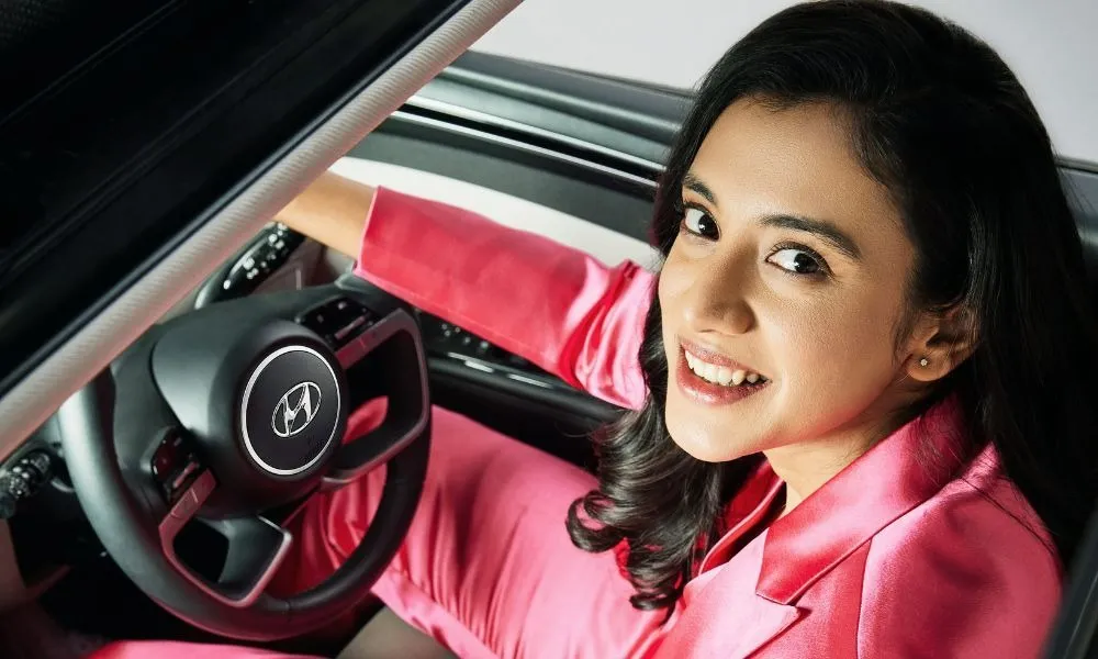 Smriti Mandhana smiling while driving a car in casual setting