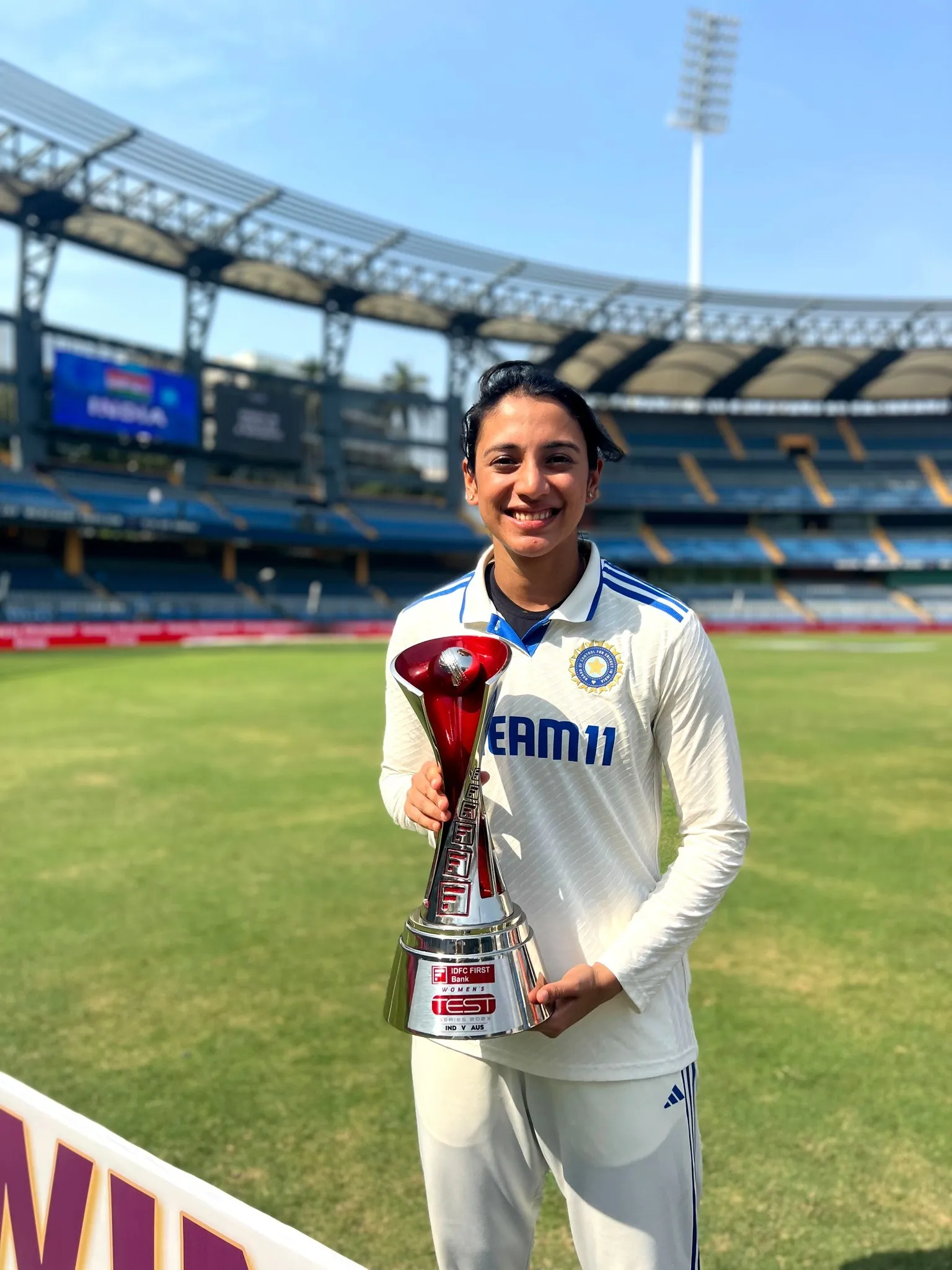 Smriti Mandhana Smiling with Trophy on Ground wallpaper