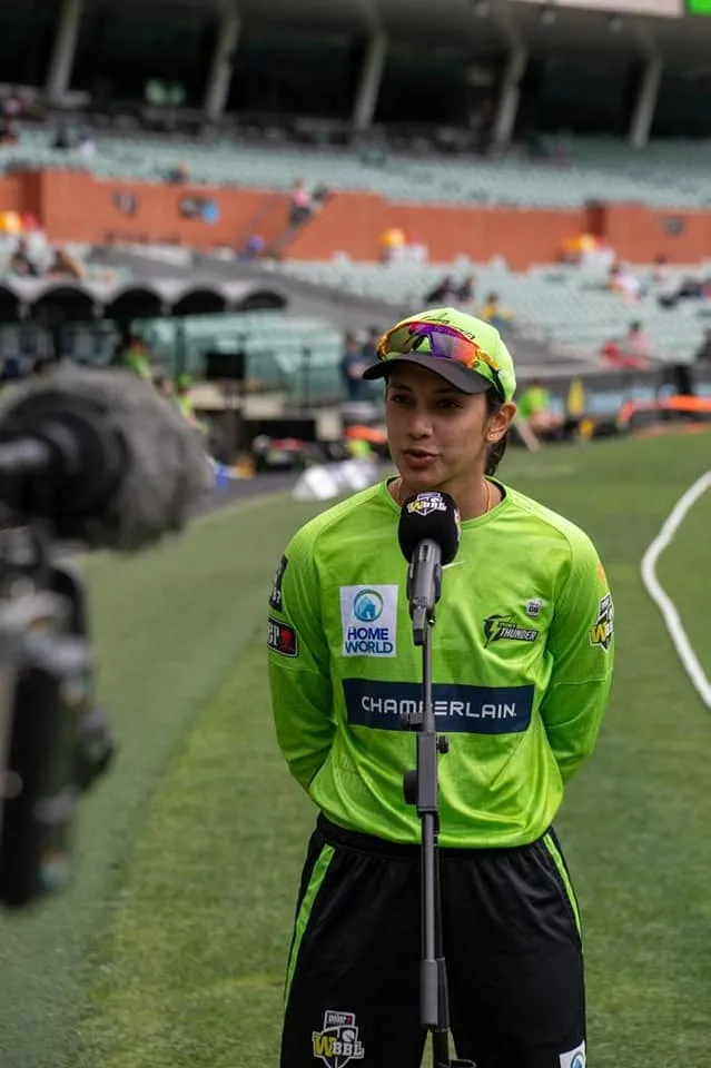 Smriti Mandhana walking on cricket field with helmet