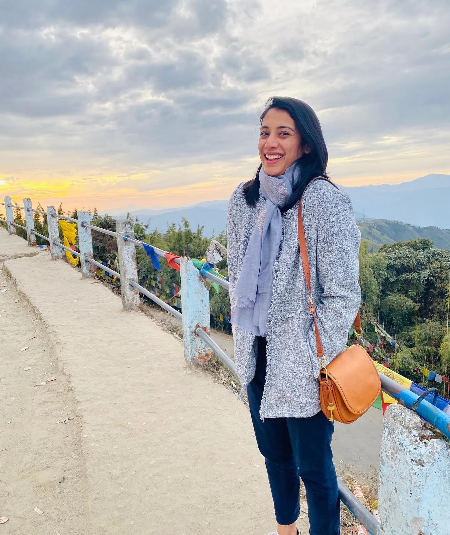 Smriti Mandhana walking on path with mountain view behind