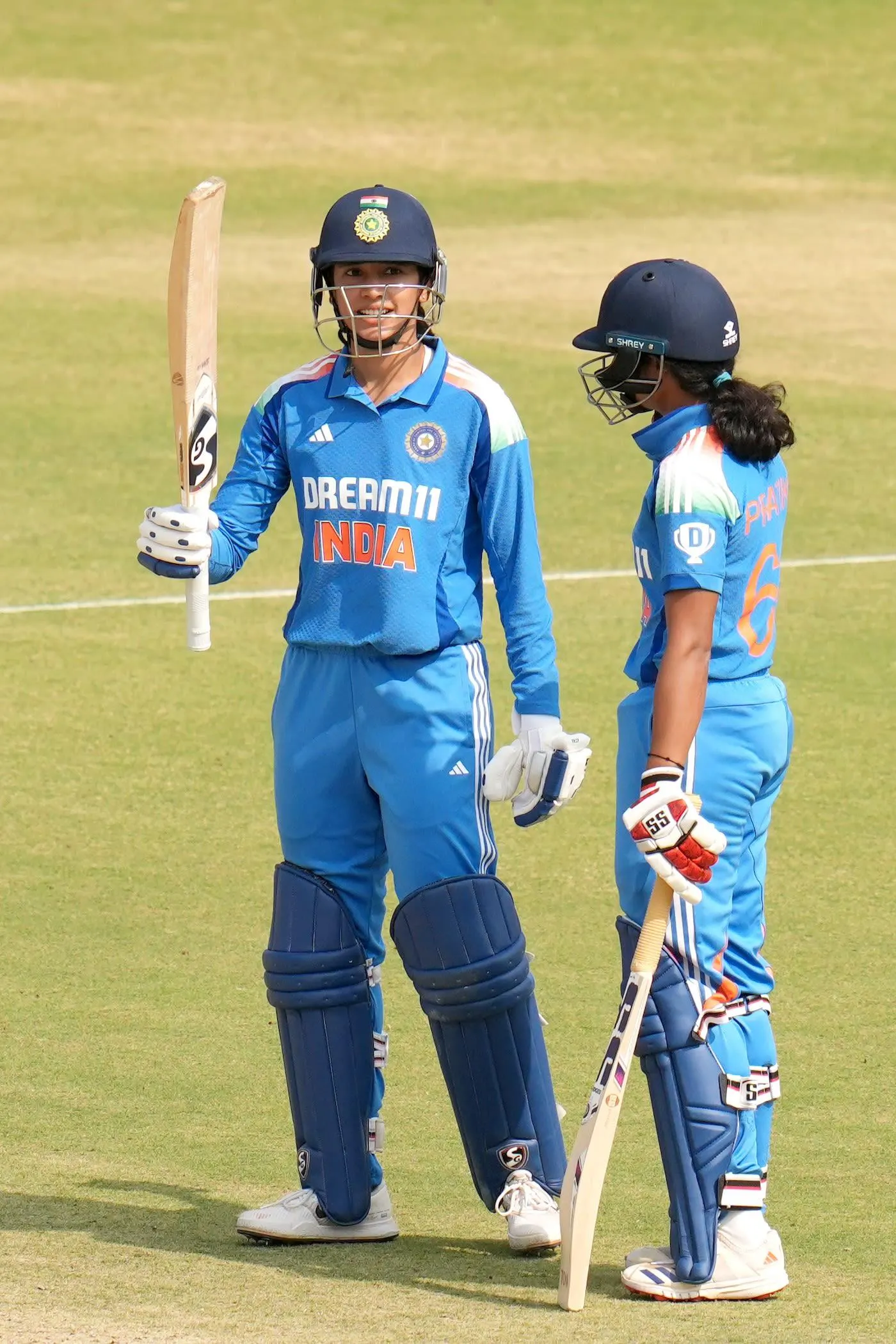 Smriti Mandhana walking with teammate on cricket field