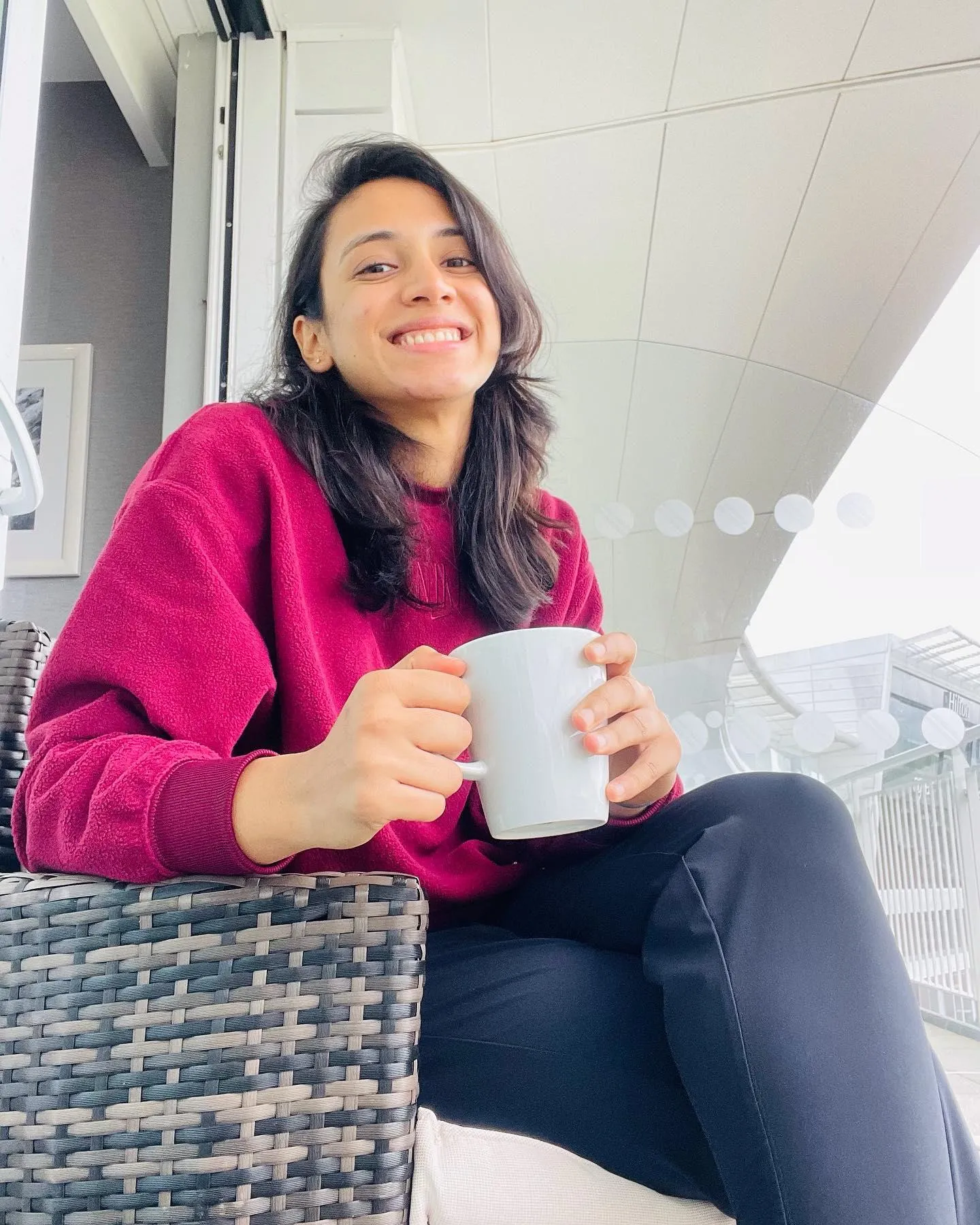 Smriti Mandhana with coffee mug in a modern indoor setting
