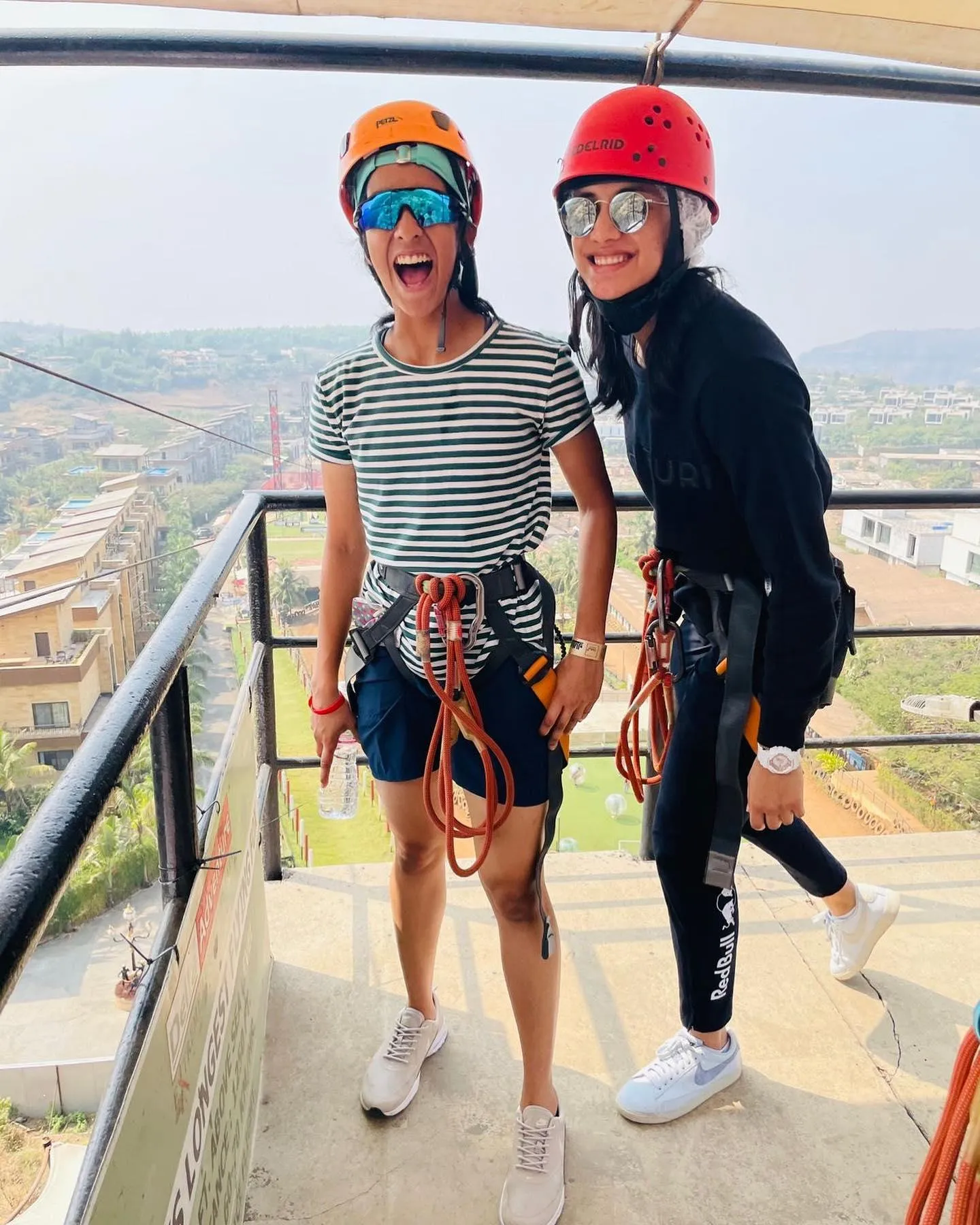 Smriti posing on a cliff with helmet and friend wallpaper