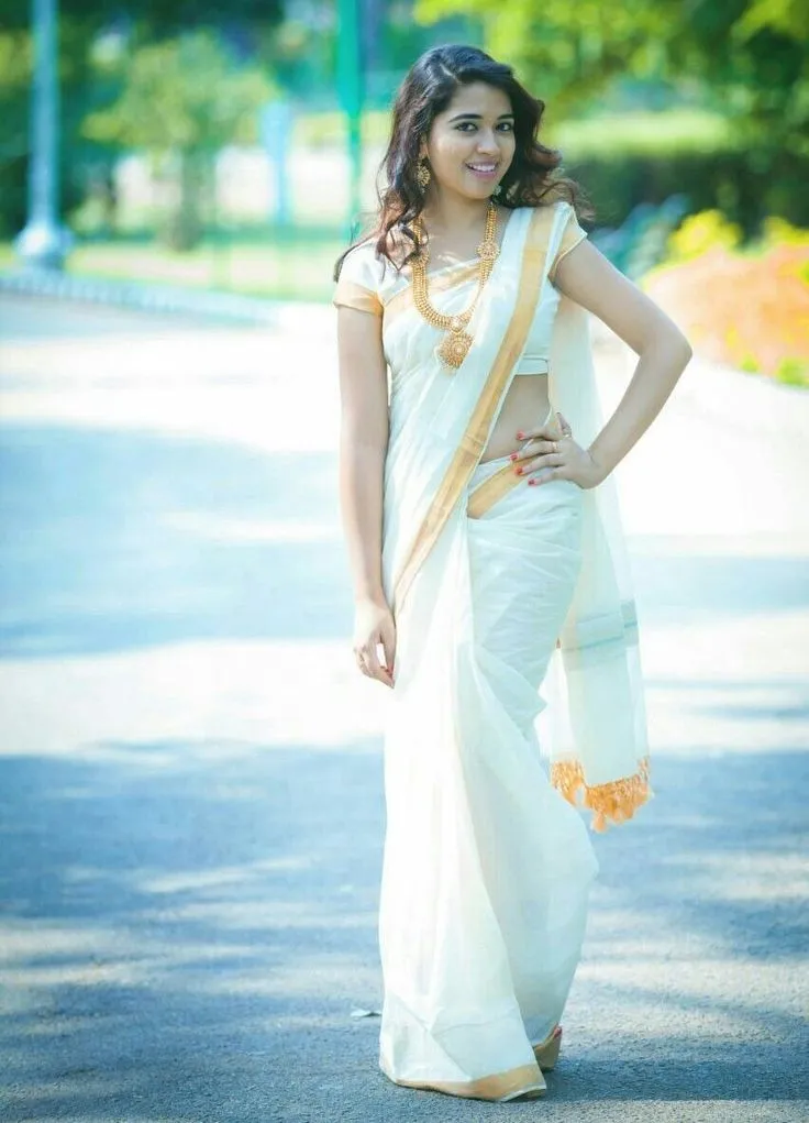Ahalya Suresh wearing an Onam saree standing on the road
