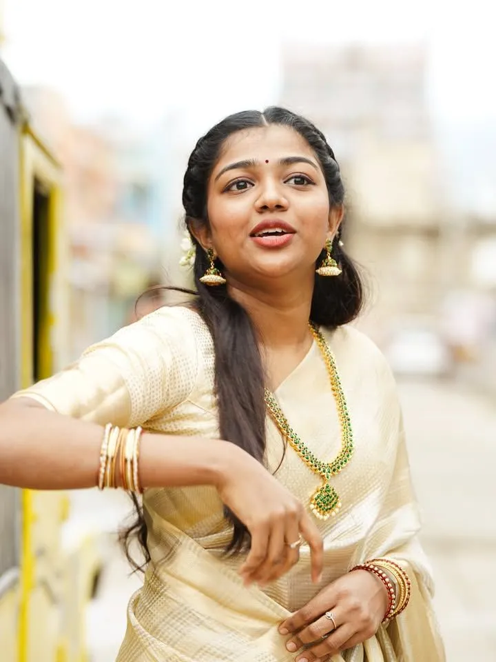 Amala Shaji in a traditional Onam saree standing outdoors