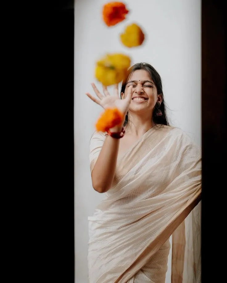 Ananthika Sanilkumar is throwing orange and yellow flowers