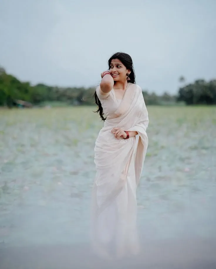 Ananthika Sanilkumar standing near pond wearing Onam saree