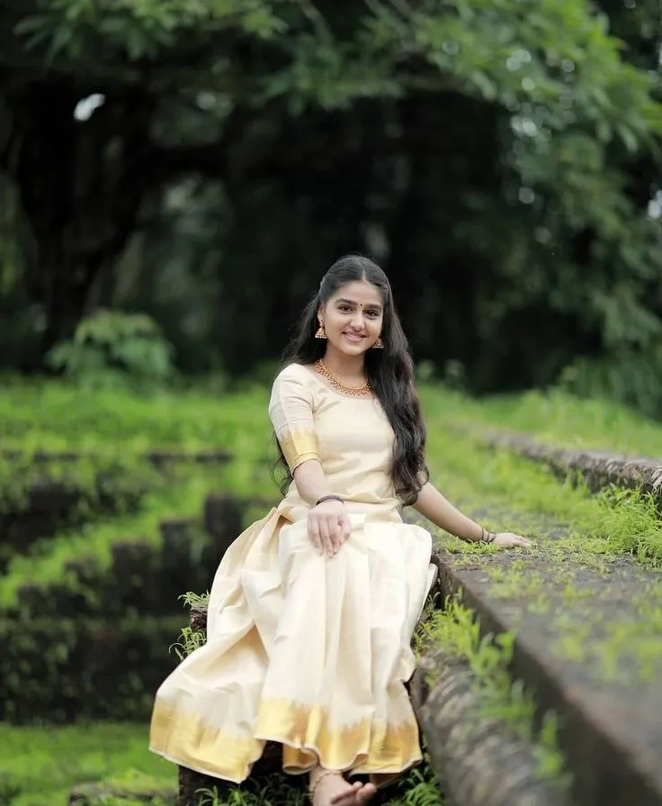 Anaswara Rajan in traditional Kerala dress sitting outdoors