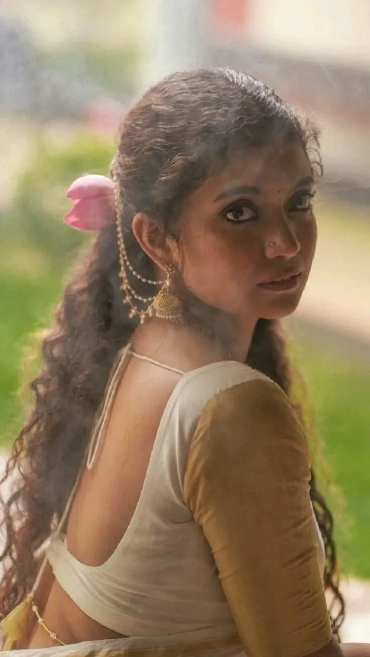 Anna Ben in a white and golden colour saree looking back