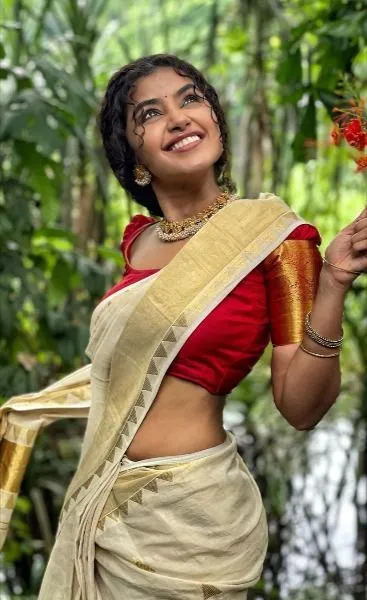 Anupama Parameswaran in a Kerala saree standing near trees